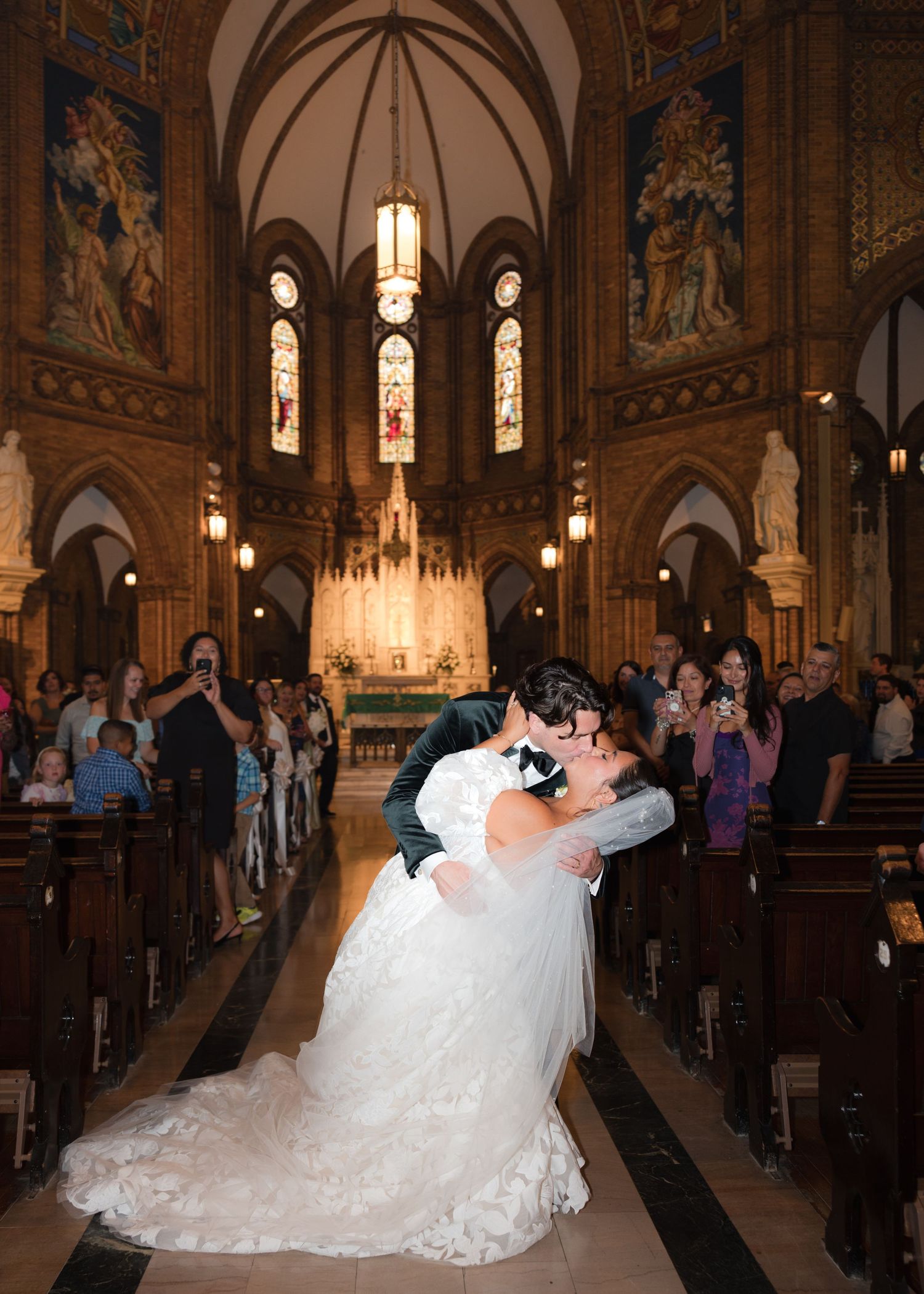 Wedding couple shares a romantic dip in an ornate cathedral with vaulted ceilings.