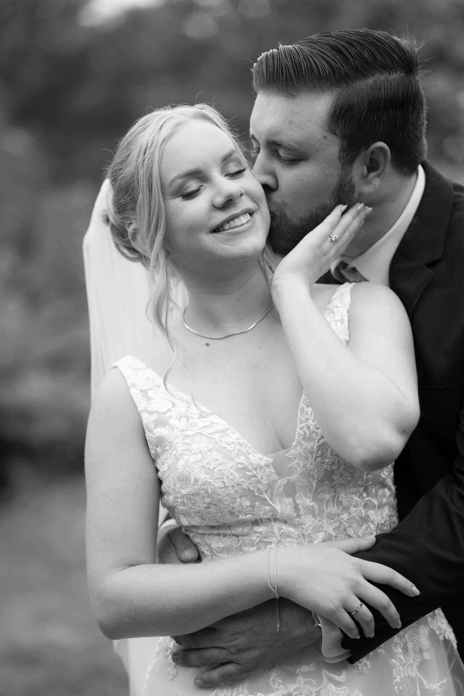Intimate black and white wedding portrait showing tender moments between newlyweds.