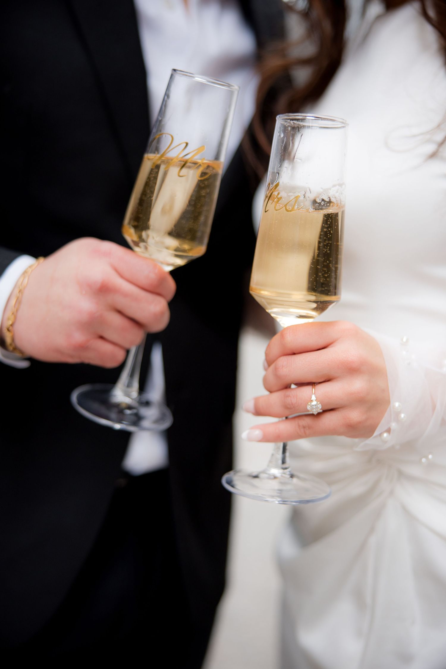 Bride and groom holding champagne flutes with Mr. and Mrs. gold lettering at their wedding reception.