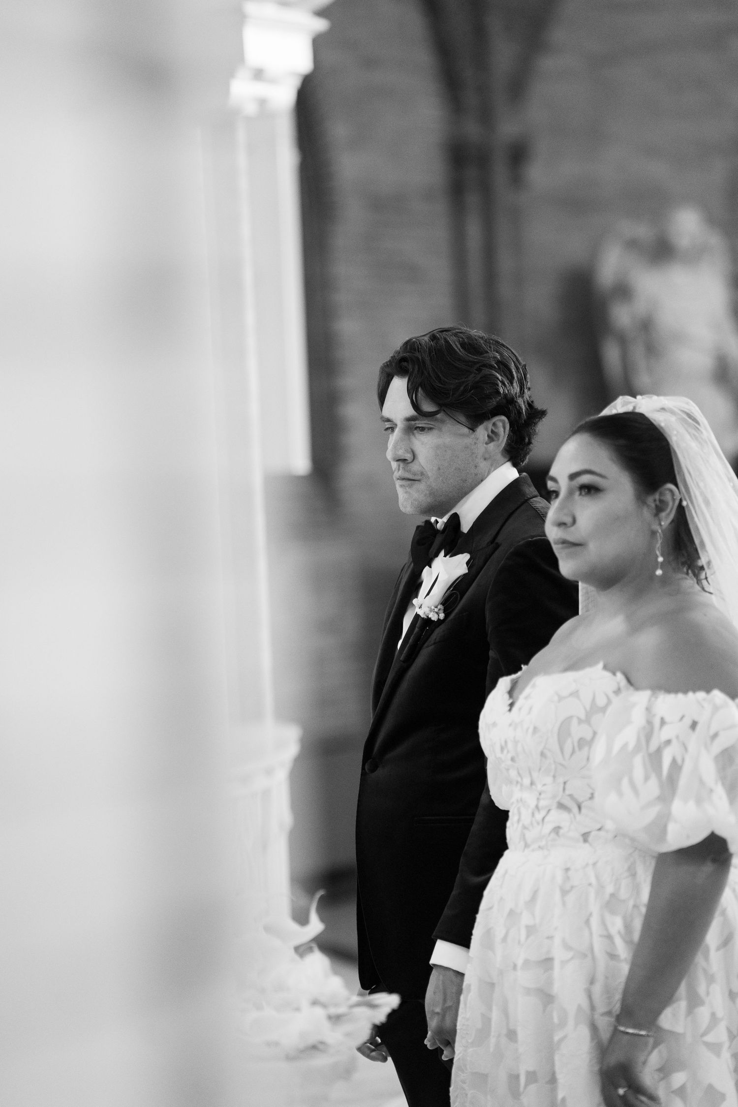 Black and white wedding portrait taken through architectural columns.