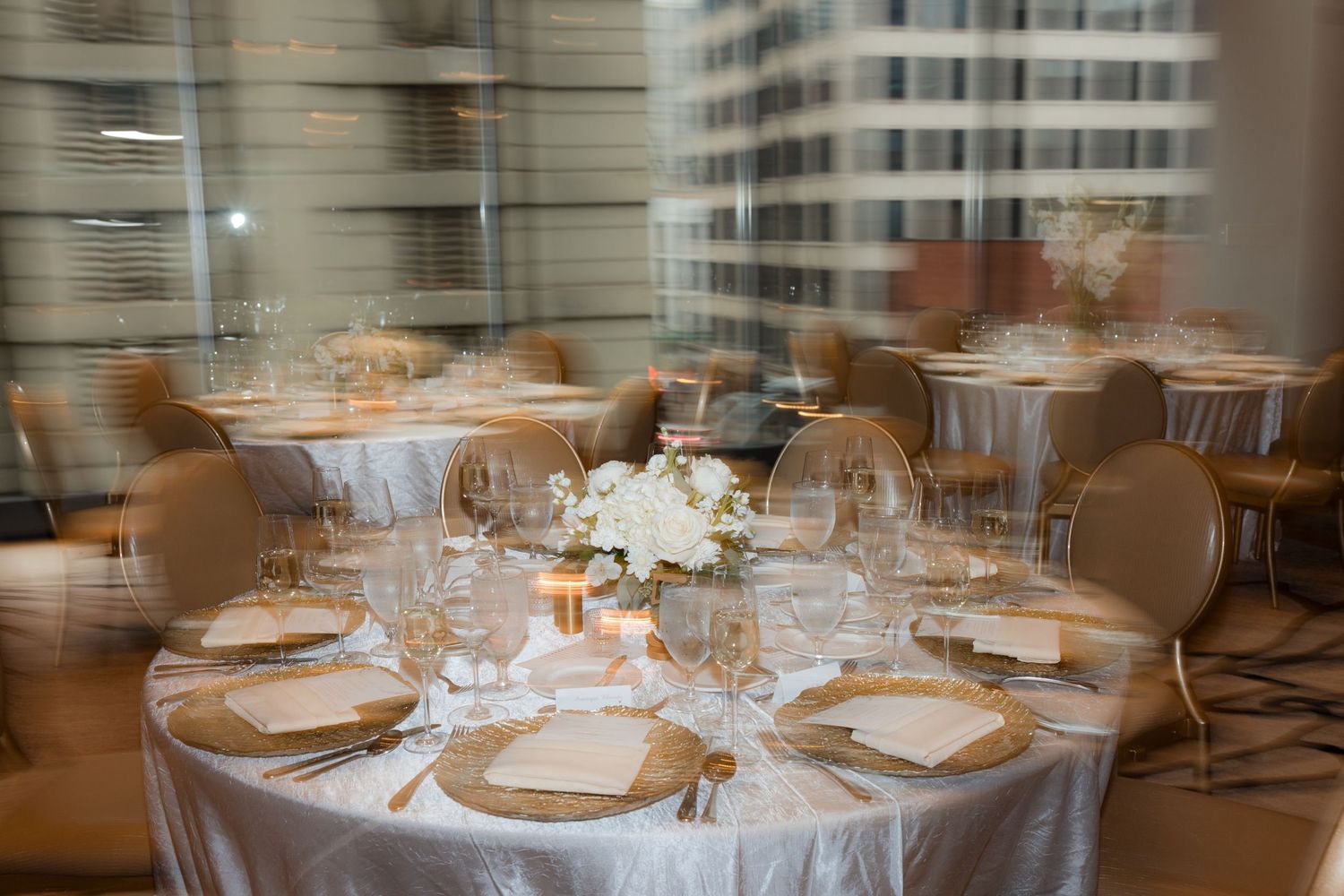 Elegant wedding reception table settings with white linens and crystal glassware.