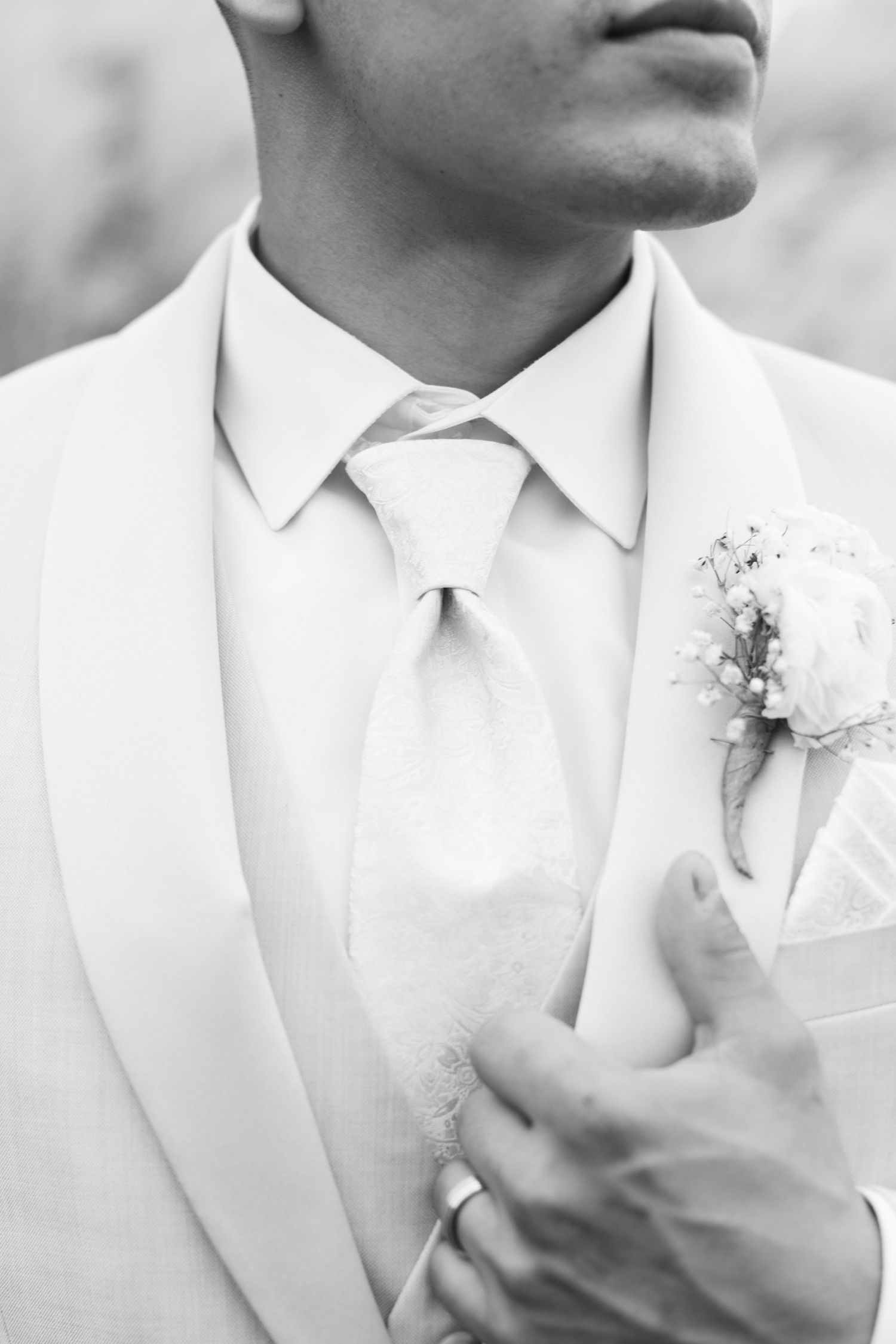 Close up detail of a white tuxedo with tie and boutonniere in black and white.
