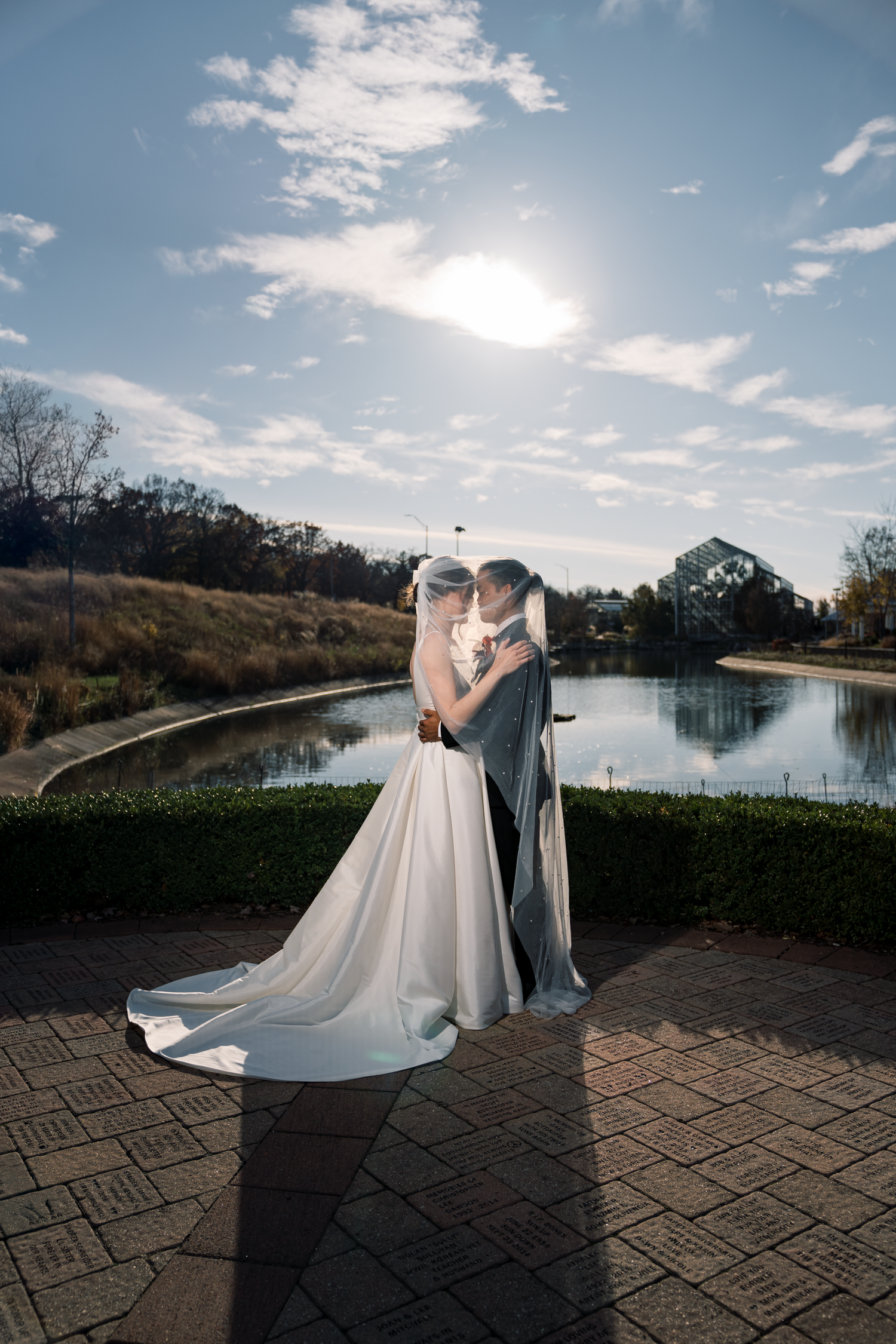 Romantic wedding portraits by a lake with dramatic sky and shadows.