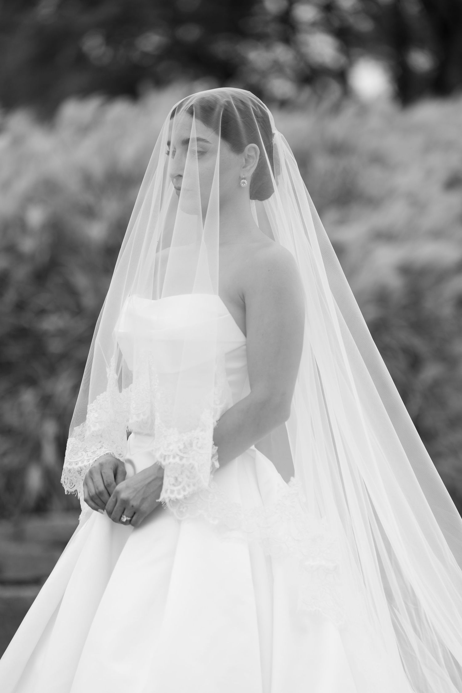 Black and white portrait of bride in classic strapless gown with cathedral length veil.