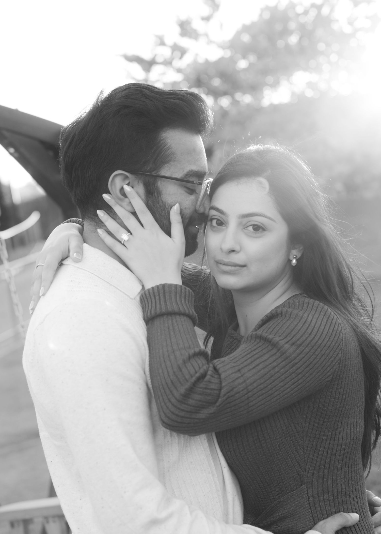 Black and white photo of a romantic couple embracing outdoors, woman tenderly touching mans face.