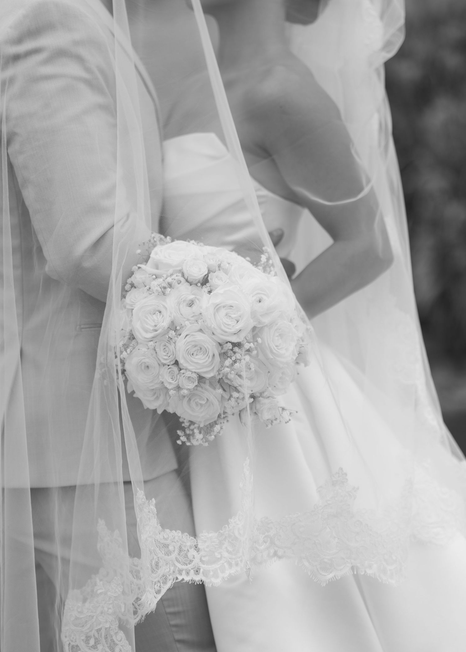 Elegant white wedding bouquet with roses and lace details on a bridal gown.