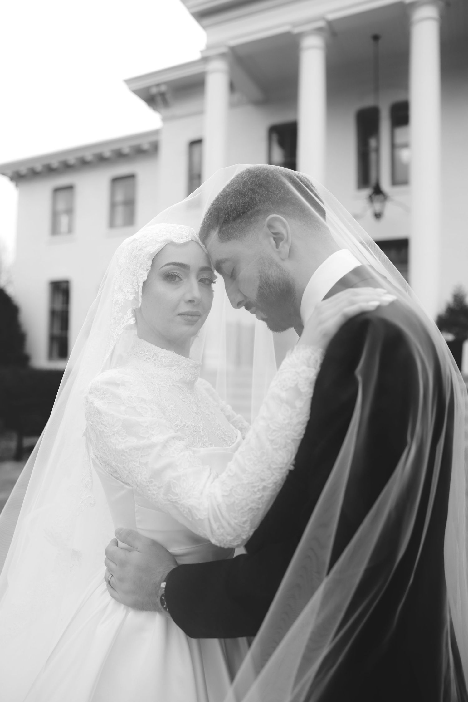 Romantic wedding portrait in front of classic white columned building.