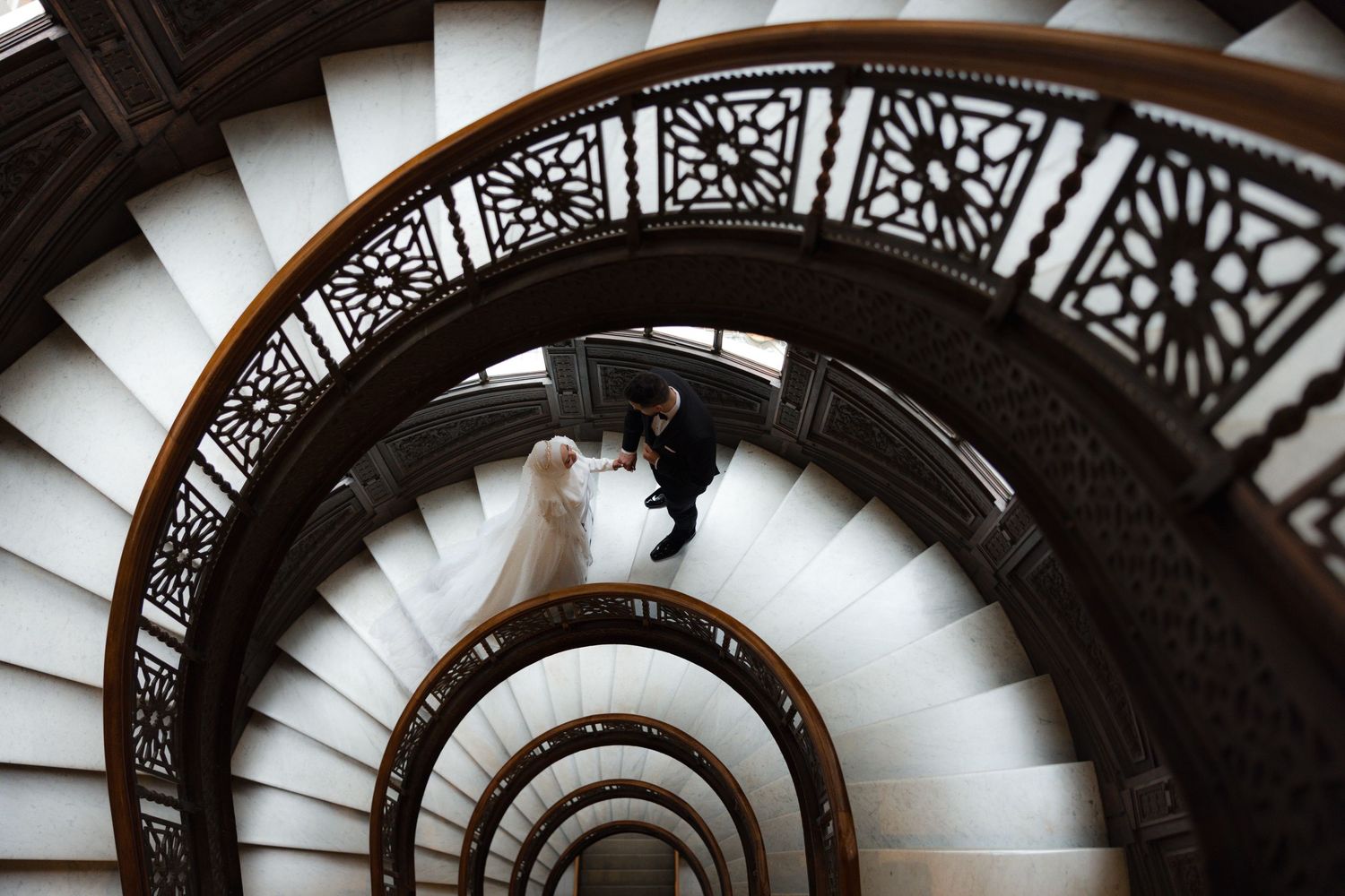 Dramatic black and white spiral staircase photo with intricate architectural details.