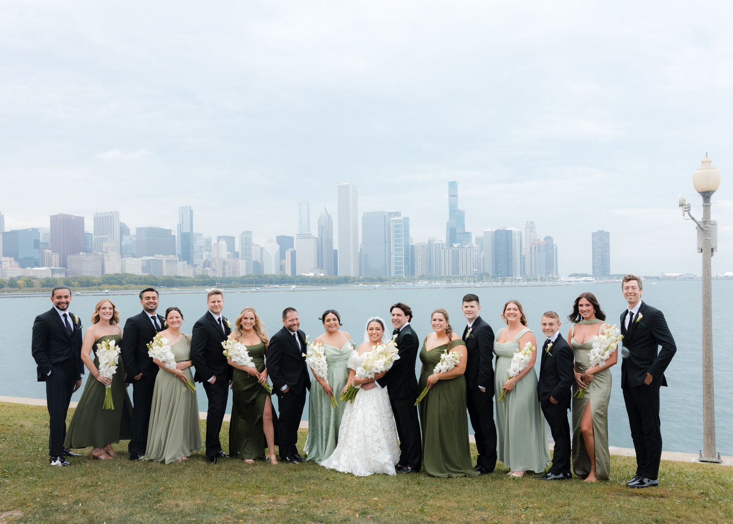 Wedding party poses against Chicago skyline on a sunny day.