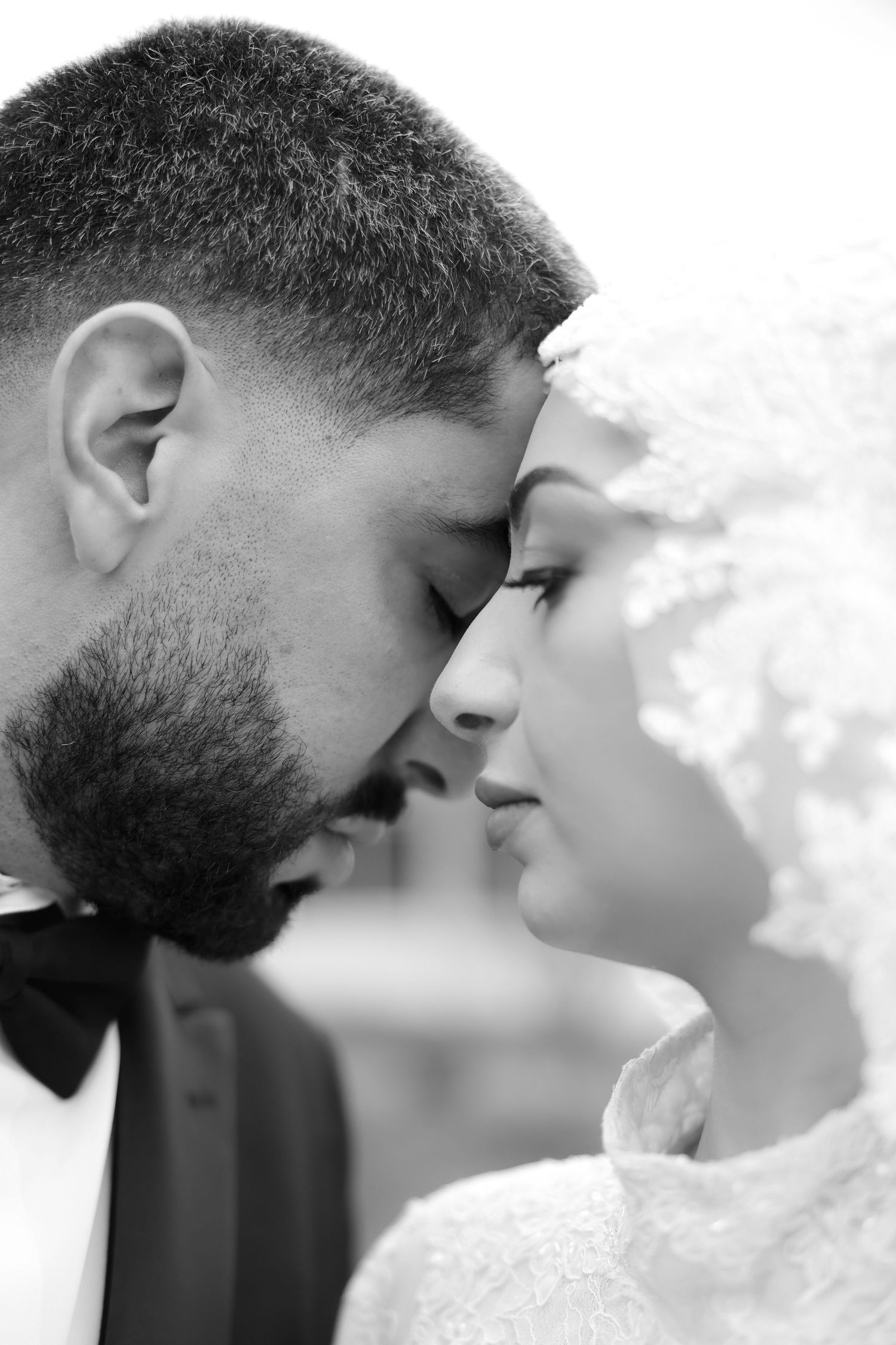 Black and white close-up of a romantic moment between a couple in wedding attire.