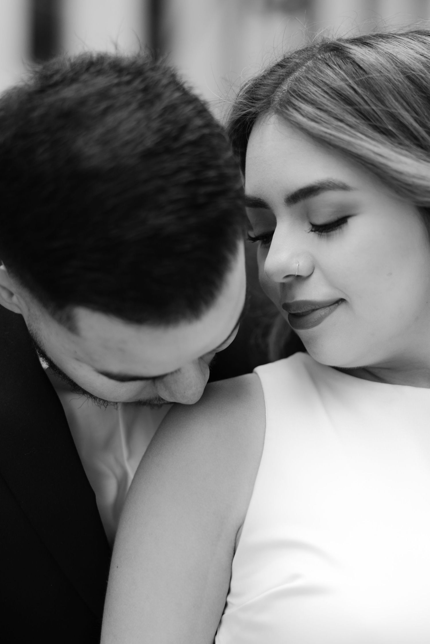Black and white photo of a romantic couple sharing an intimate moment, bride in white dress with eyes closed.