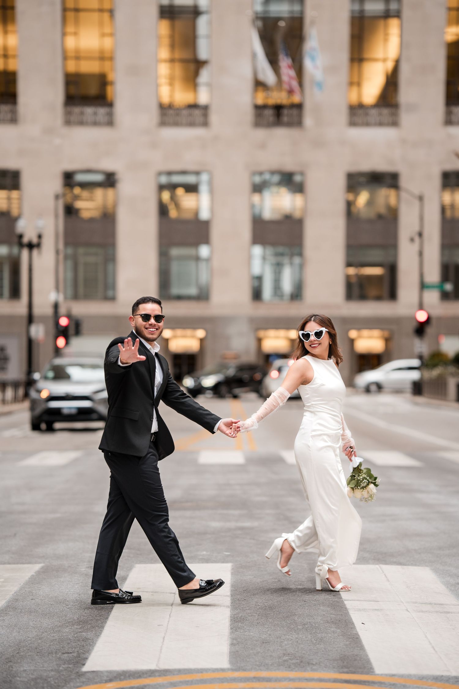 Playful wedding couple performs dramatic poses on an urban sidewalk.