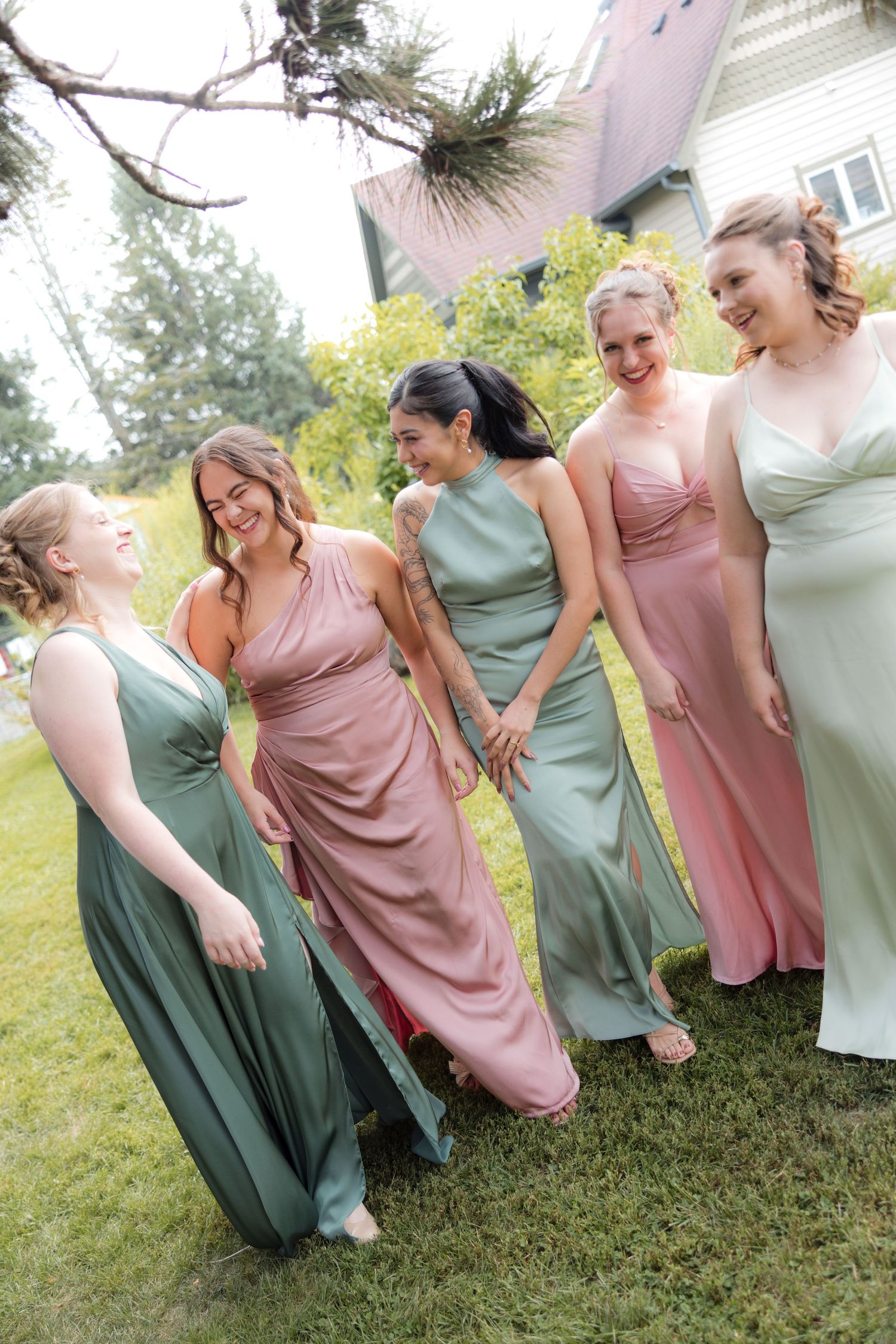 Candid moments of bridal party in pink and mint dresses laughing on grass.