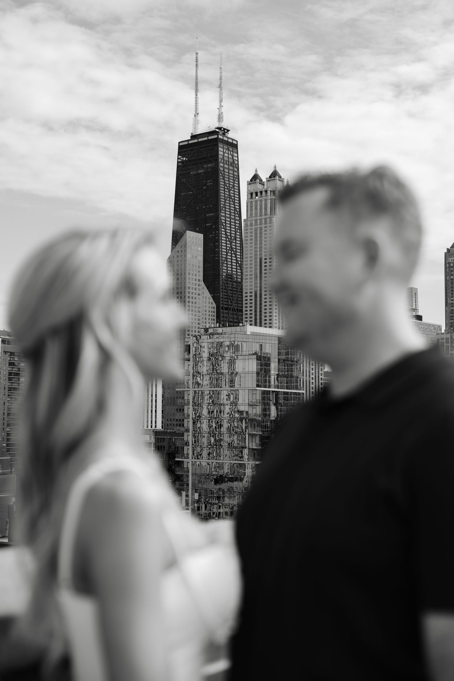 Black and white photo of a couple with Chicago skyline and Willis Tower in the background.