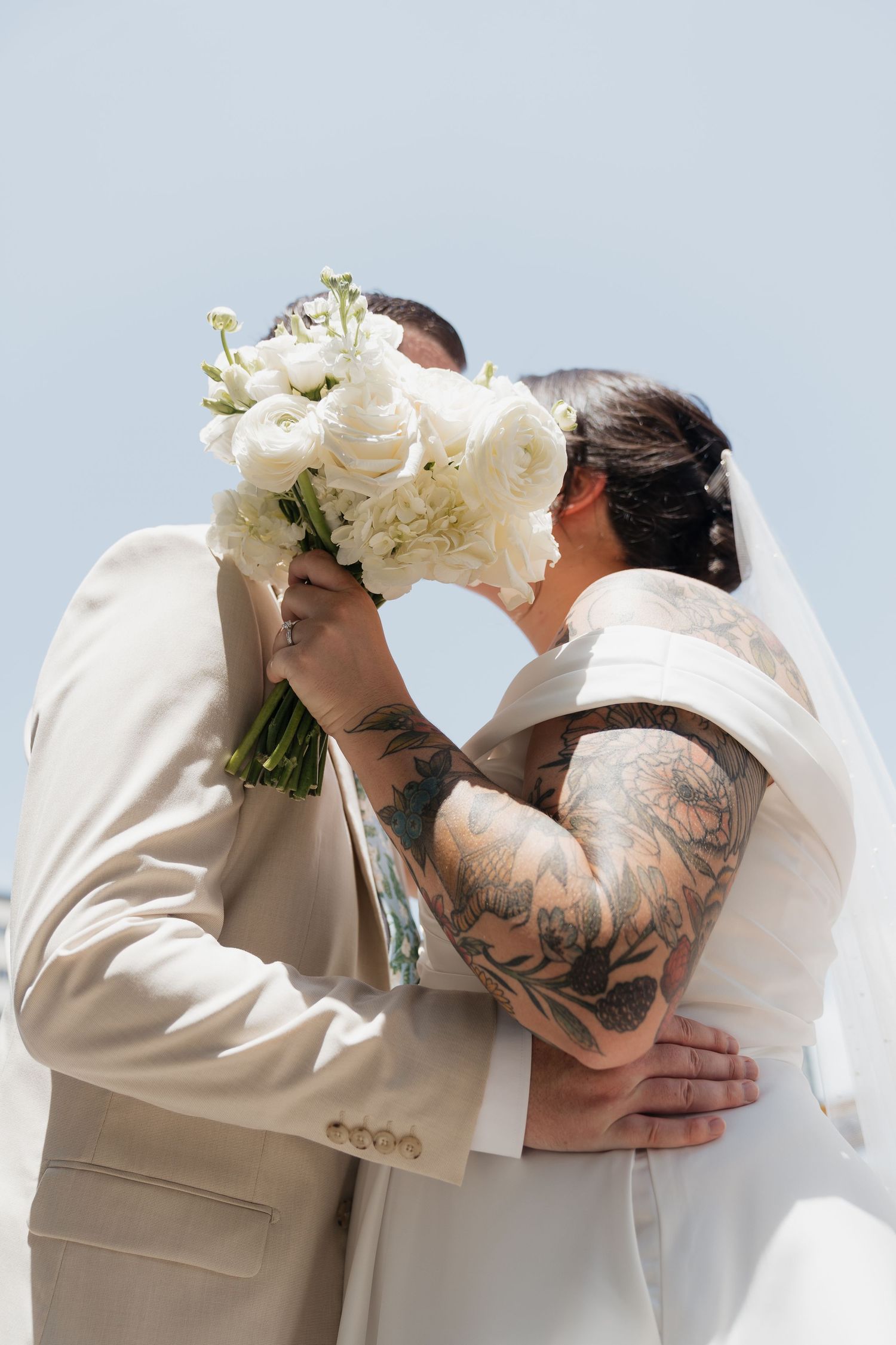 A romantic wedding moment captured in sequence showing a couple sharing a kiss while holding a white floral bouquet.