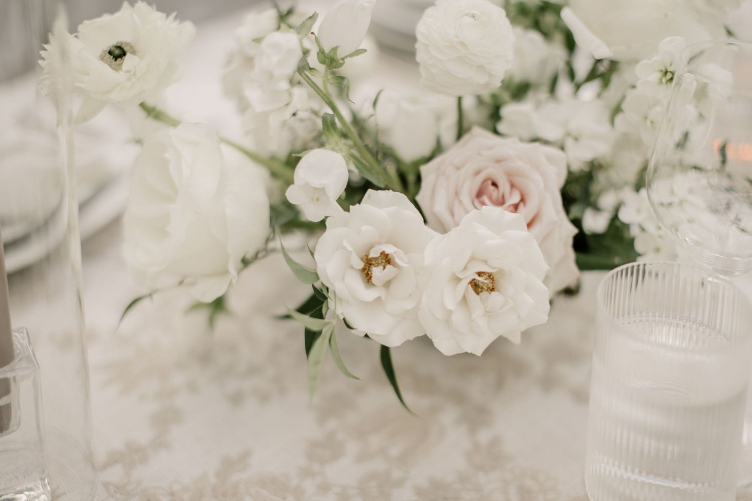 White and blush pink roses and gardenias create an elegant floral arrangement for a wedding celebration.