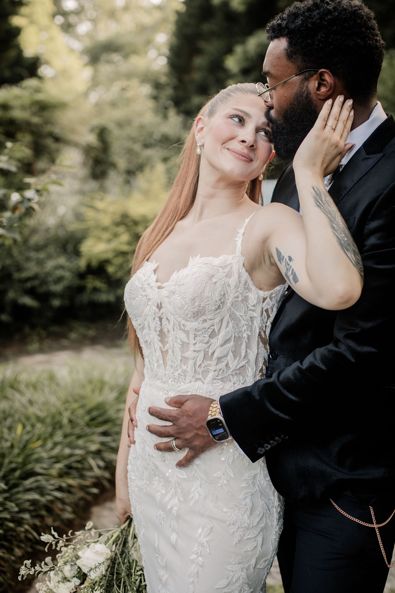An intimate wedding portrait showing a tender moment between newlyweds in a garden setting.