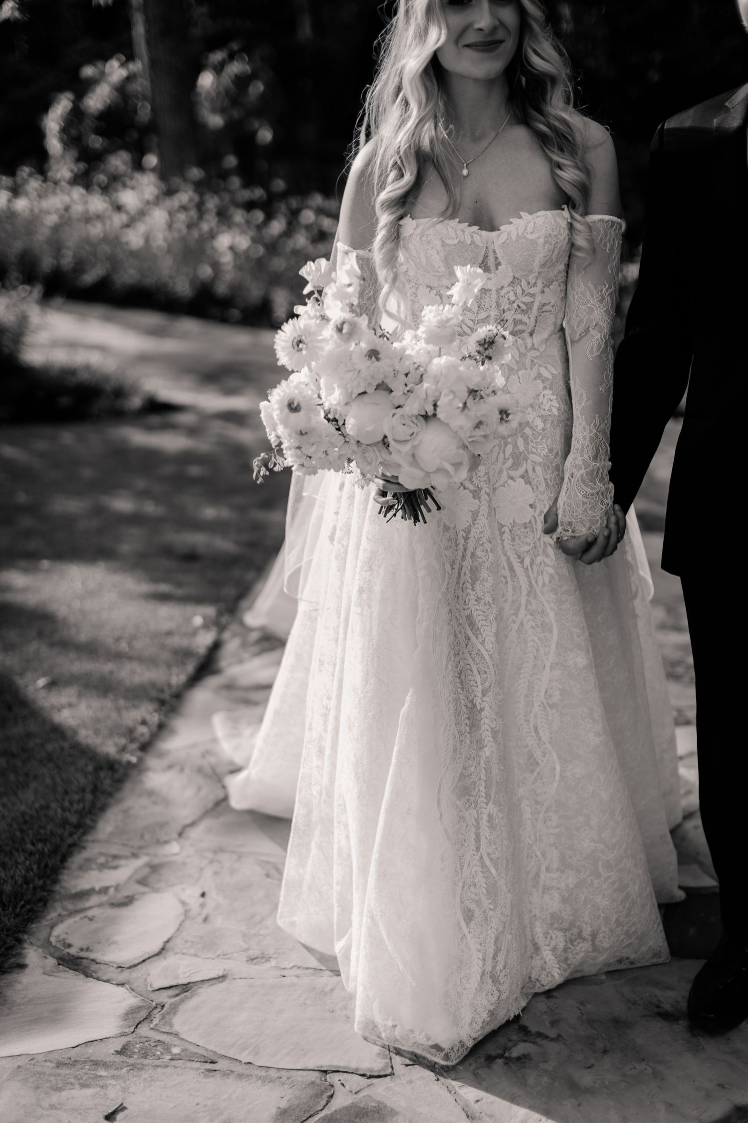 A black and white wedding photo series showing the bottom portion of an elegant lace dress with flowing fabric details.