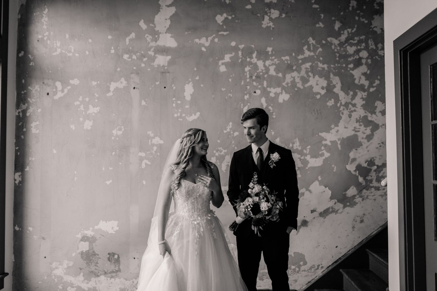 A couple shares an intimate dance together during their wedding reception in a rustic venue.