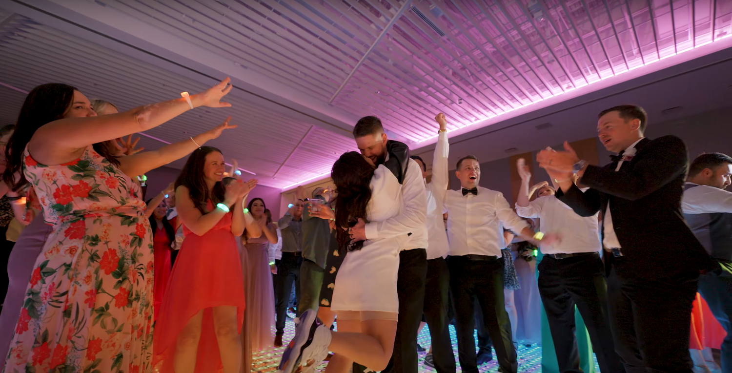 People dancing and having fun at a wedding reception with pink mood lighting and uplighting.