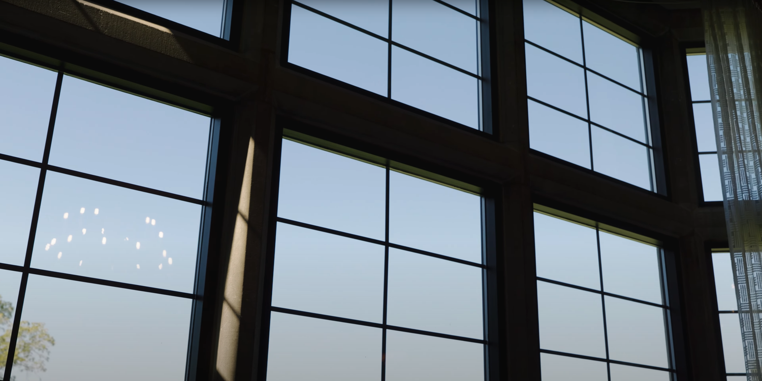 Large geometric windows with dark frames allow natural light to stream into an interior architectural space.