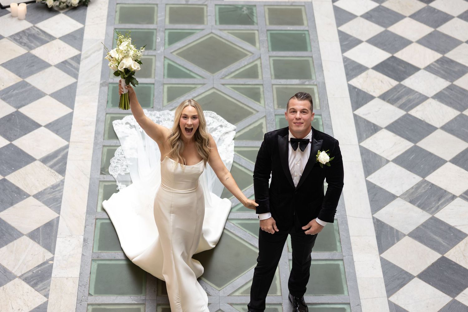 Wedding couple dancing on geometric black and white checkered floor pattern.