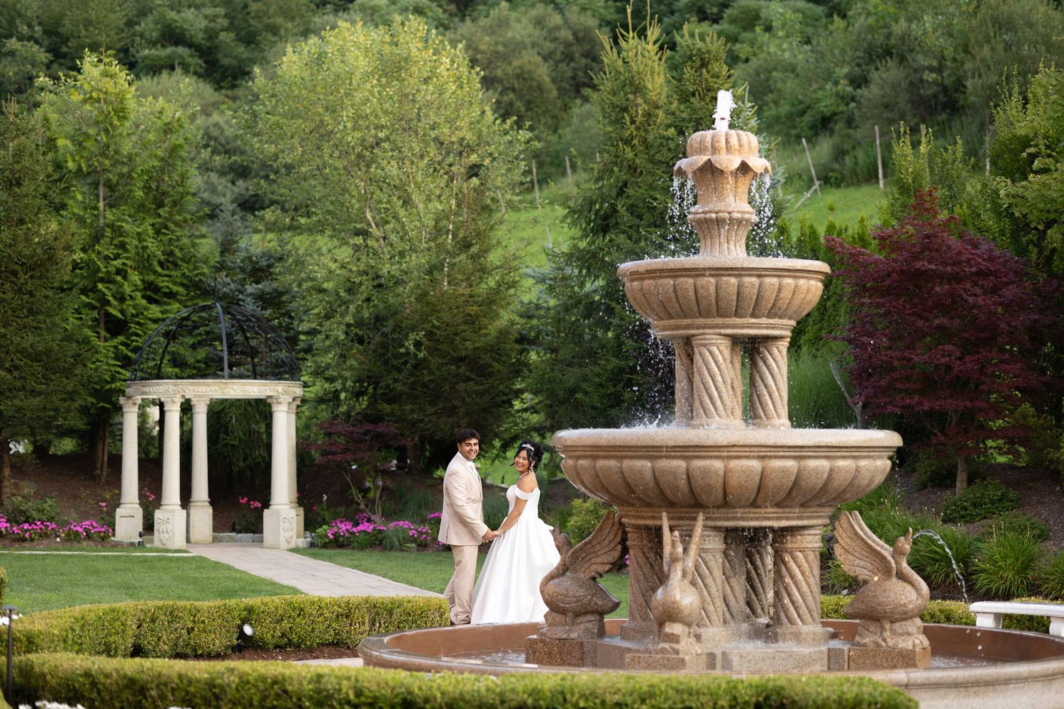 Garden wedding venue with ornate stone fountains and lush green landscaping.