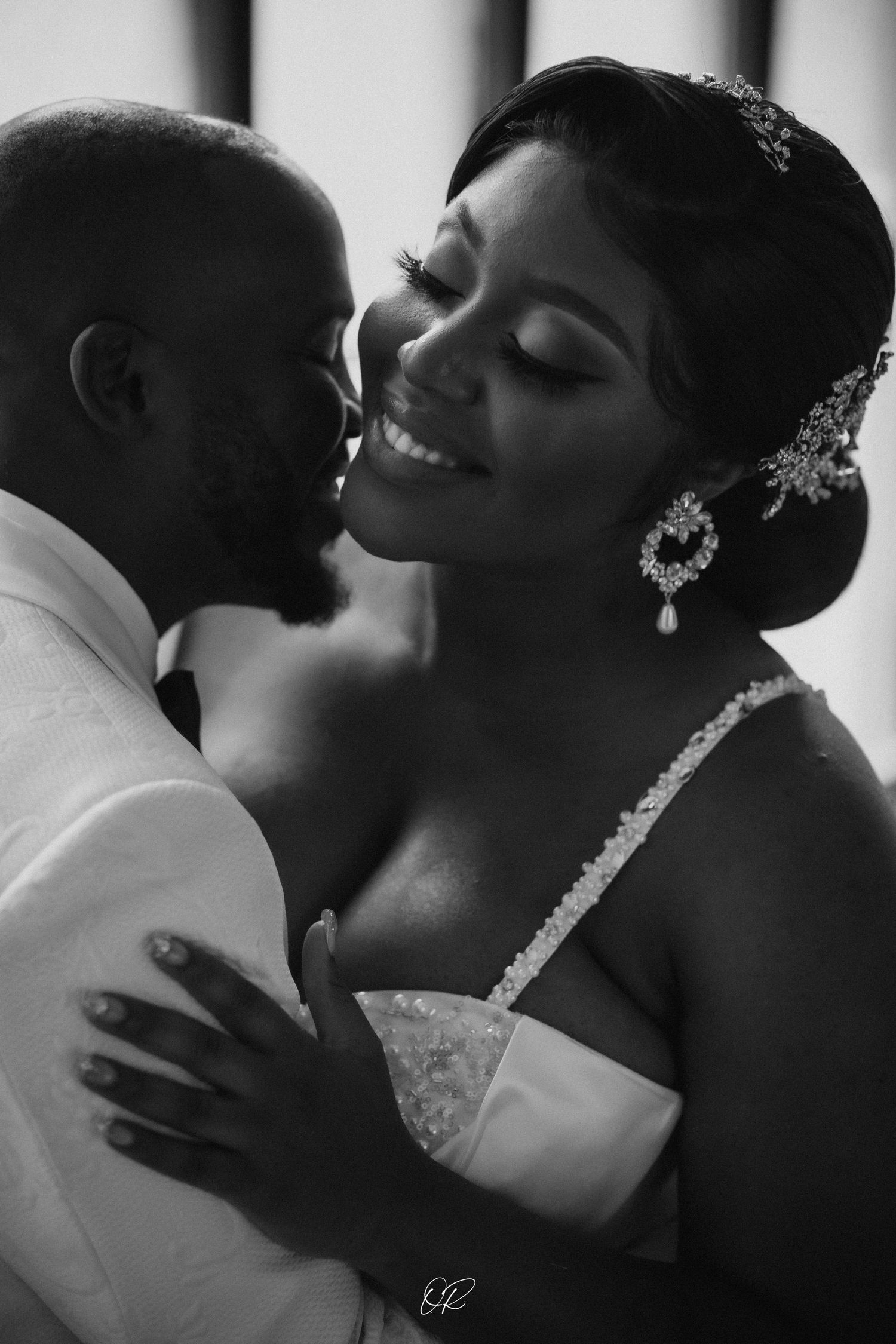 A romantic black and white wedding photograph showing a tender intimate moment between newlyweds during their special day.