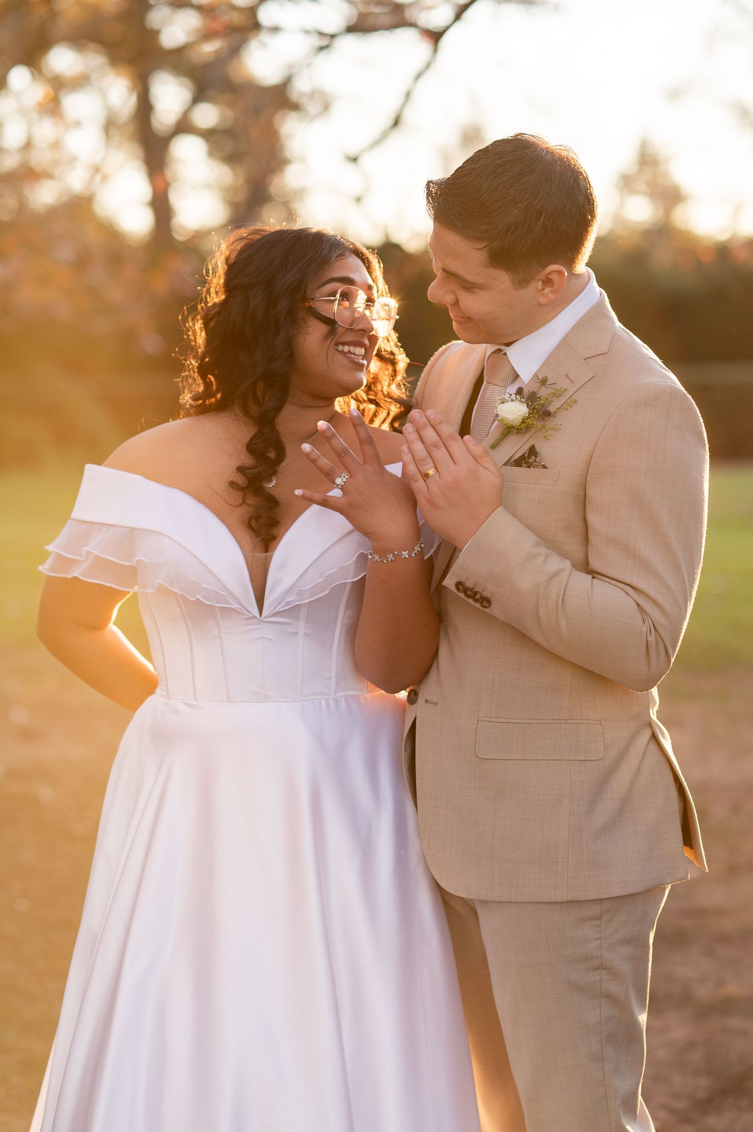 A romantic wedding couple shares an intimate moment at golden hour, with the bride in white and groom in beige.