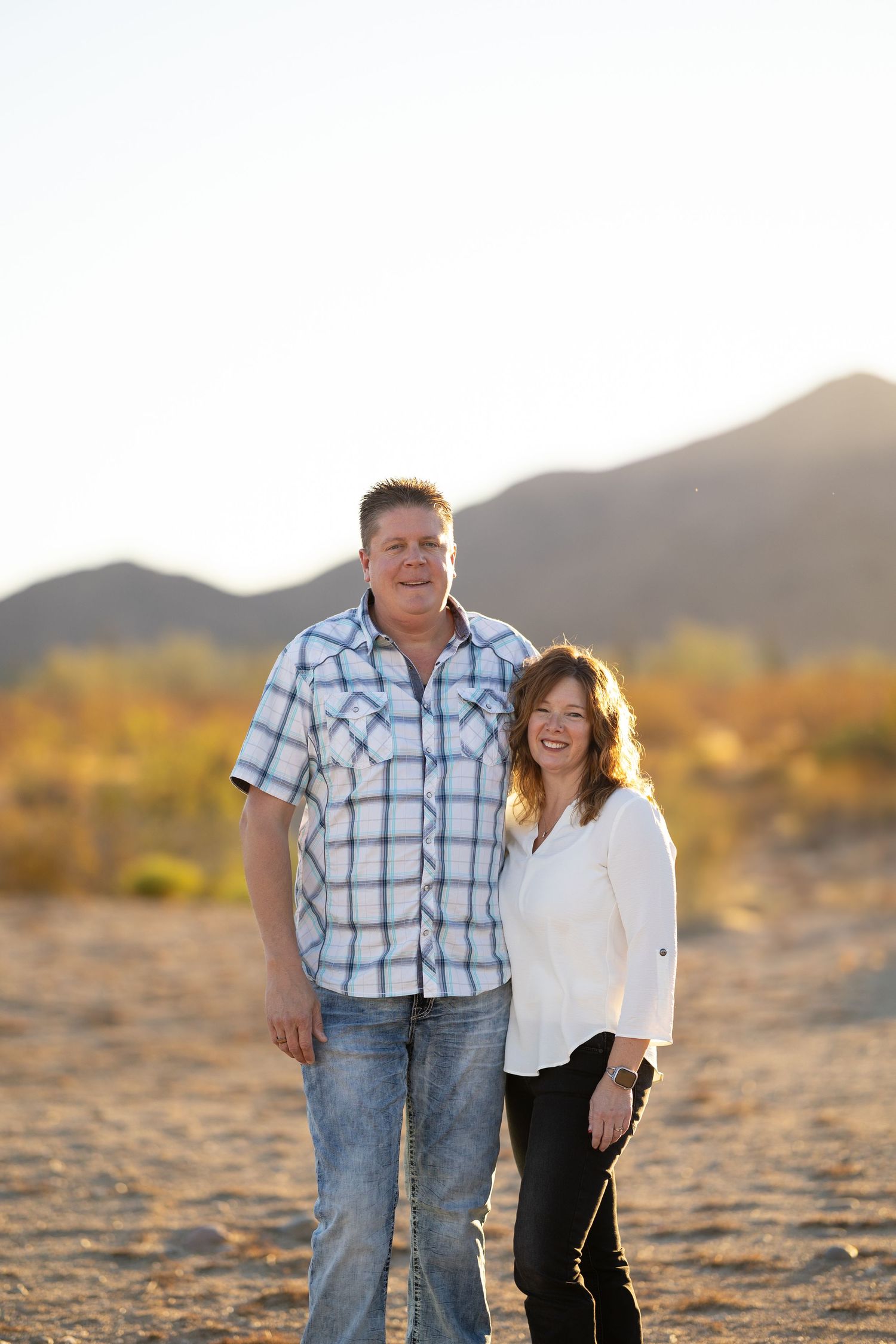 Engagement Session in the desert hugging each other looking at the camera.