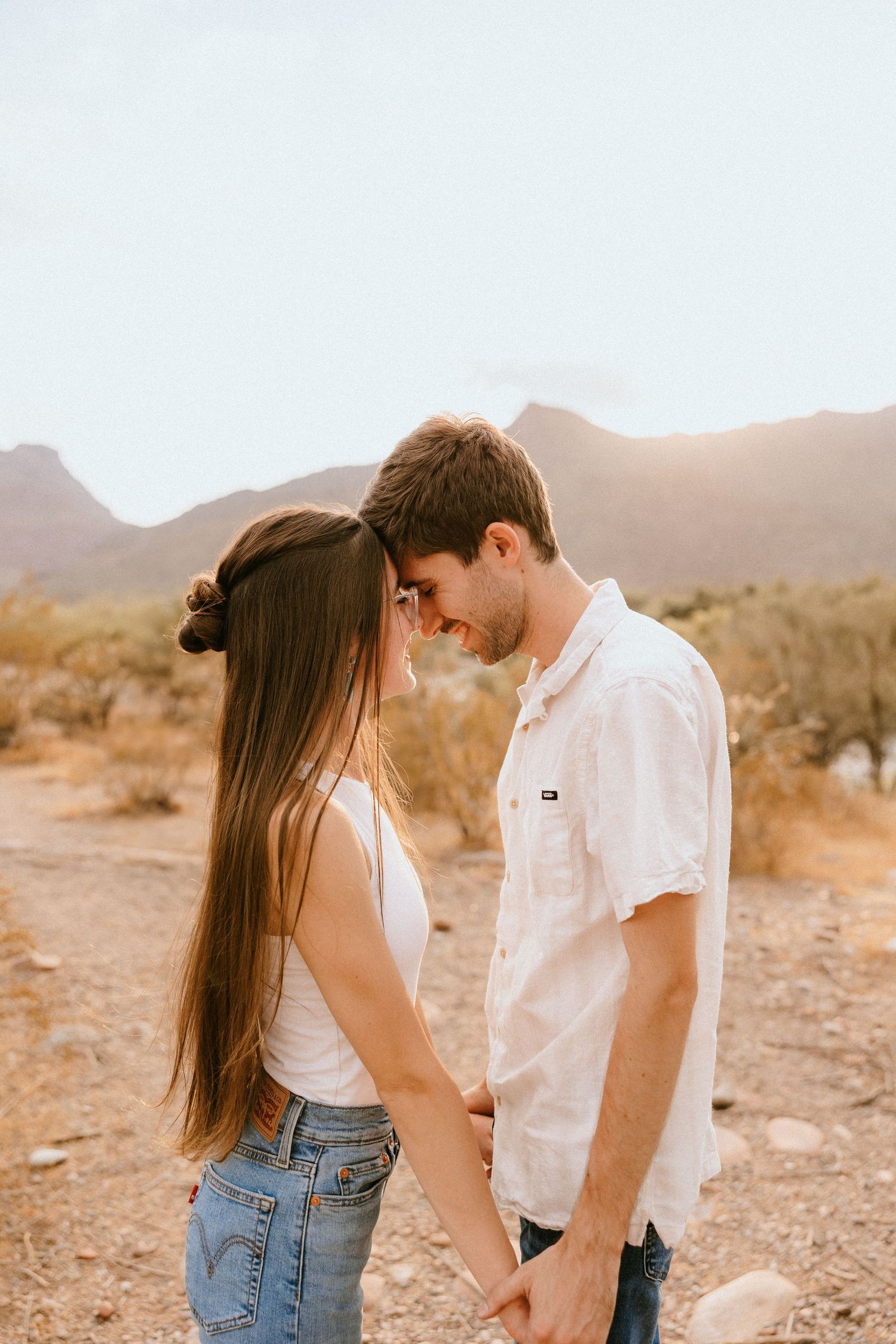 A tender moment between a couple standing close together on a desert trail.