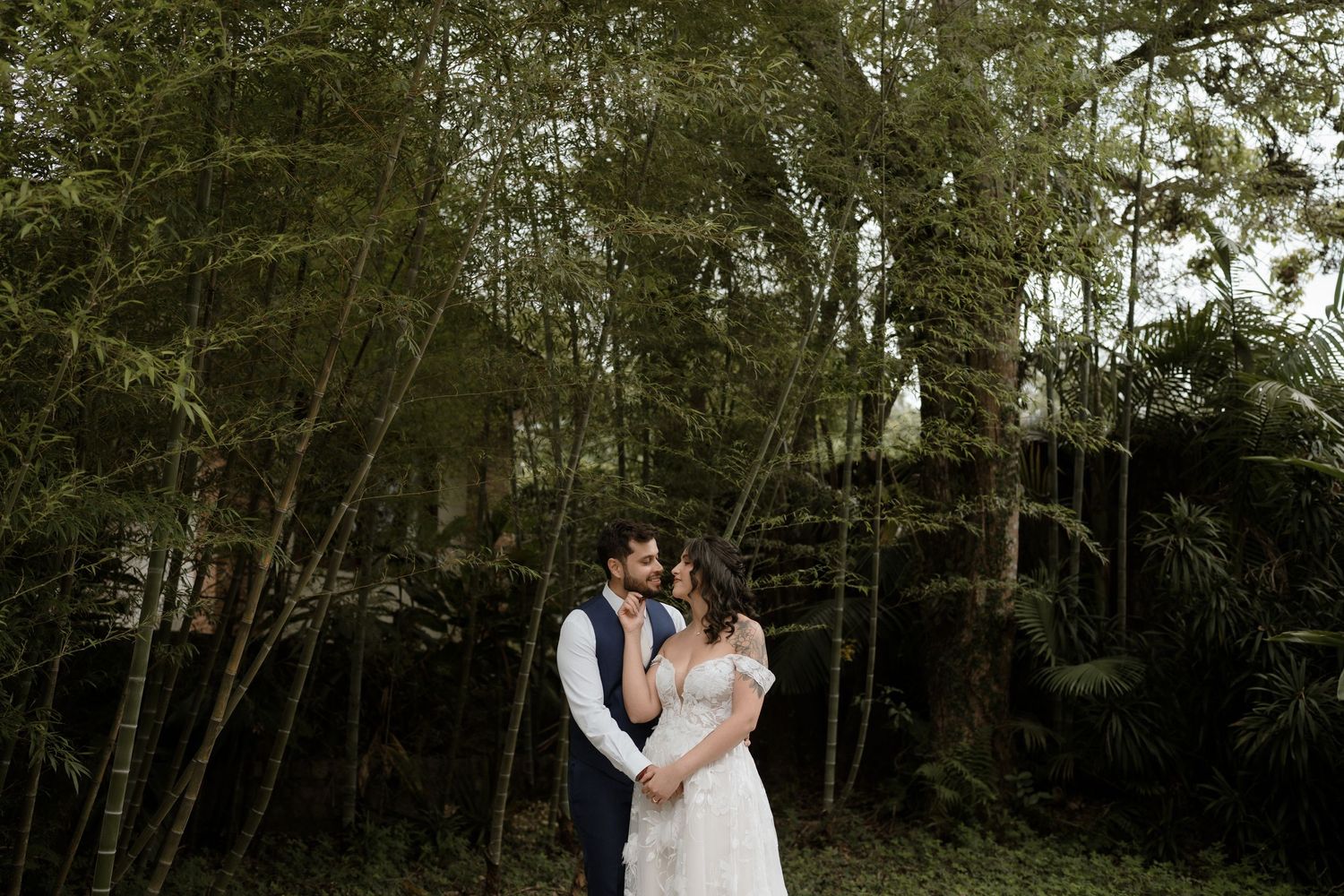 A romantic couple shares intimate moments in a wooded outdoor setting during a wedding photo session.