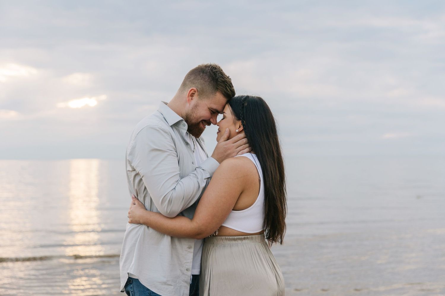 Tender embrace between couple at seaside during sunset.