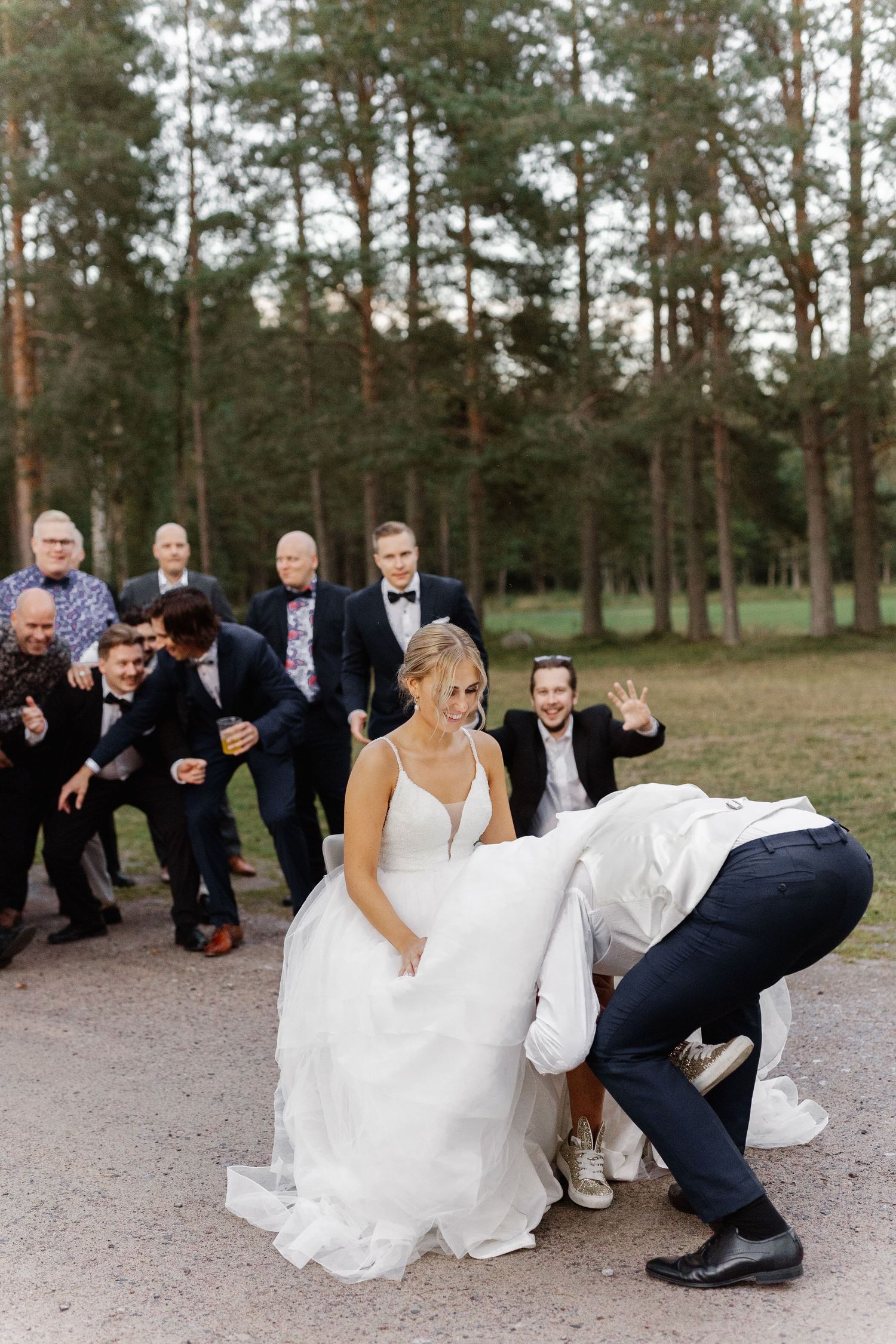 A playful wedding moment captured outdoors with guests and wedding party in formal attire.