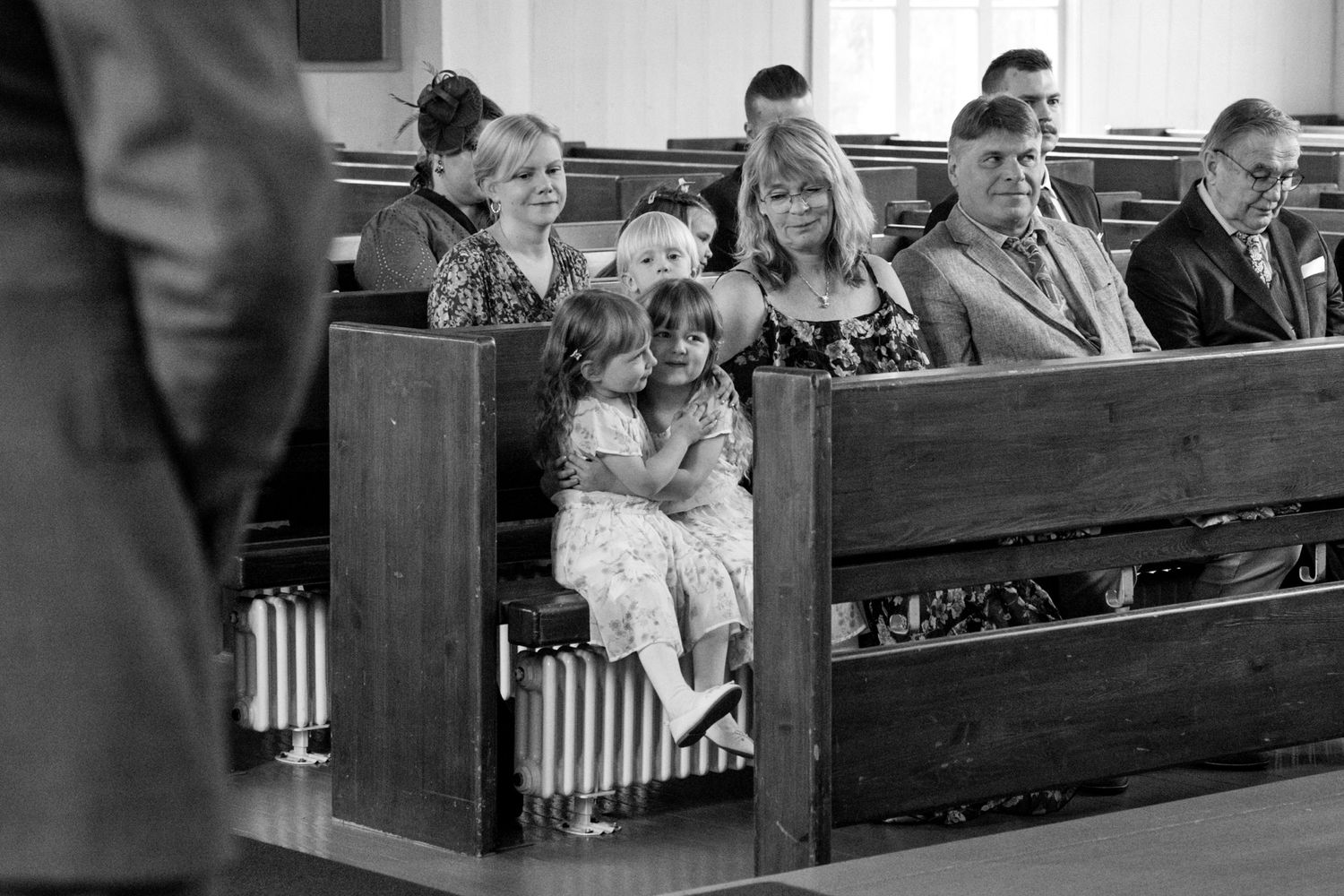 Black and white vintage photograph of people seated in wooden church pews.