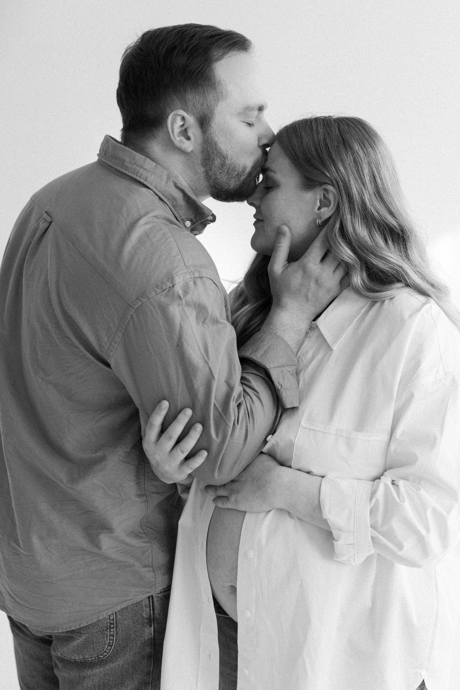A black and white photo series showing a romantic couple embracing and kissing against a white background.