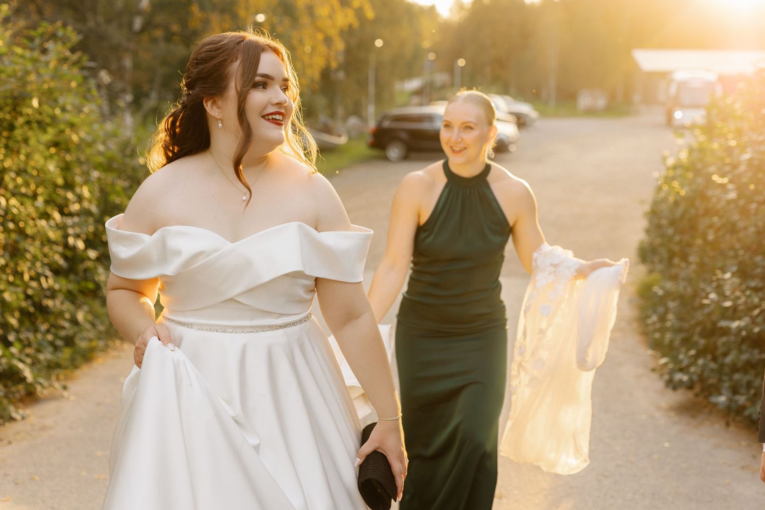 Wedding party members share a joyful moment in golden sunset light.