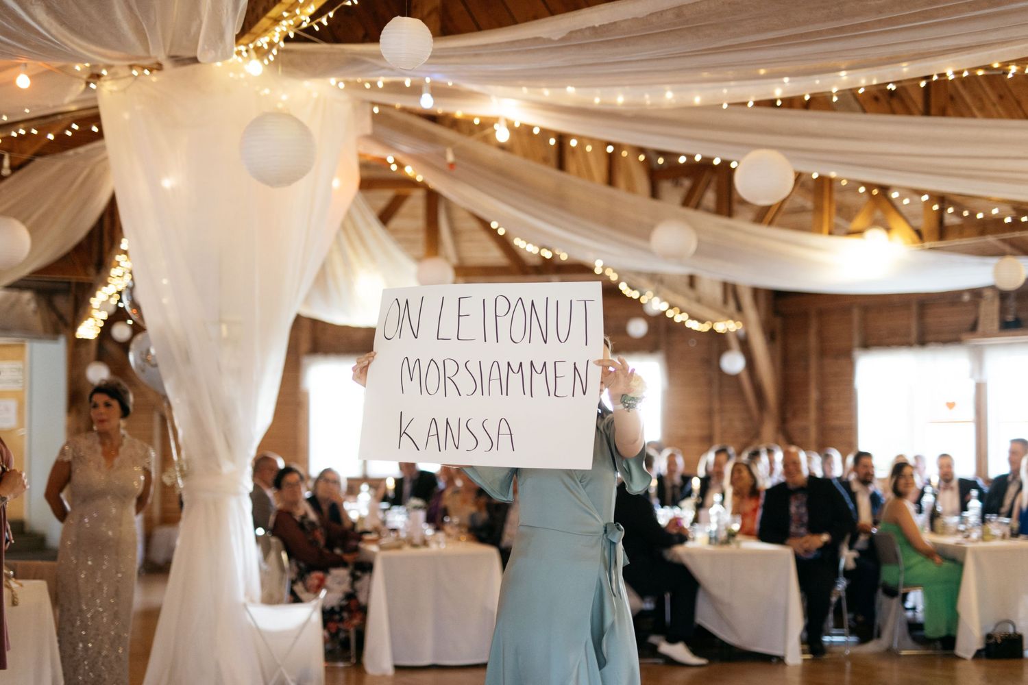 Wedding reception venue decorated with white drapes, string lights and paper lanterns.