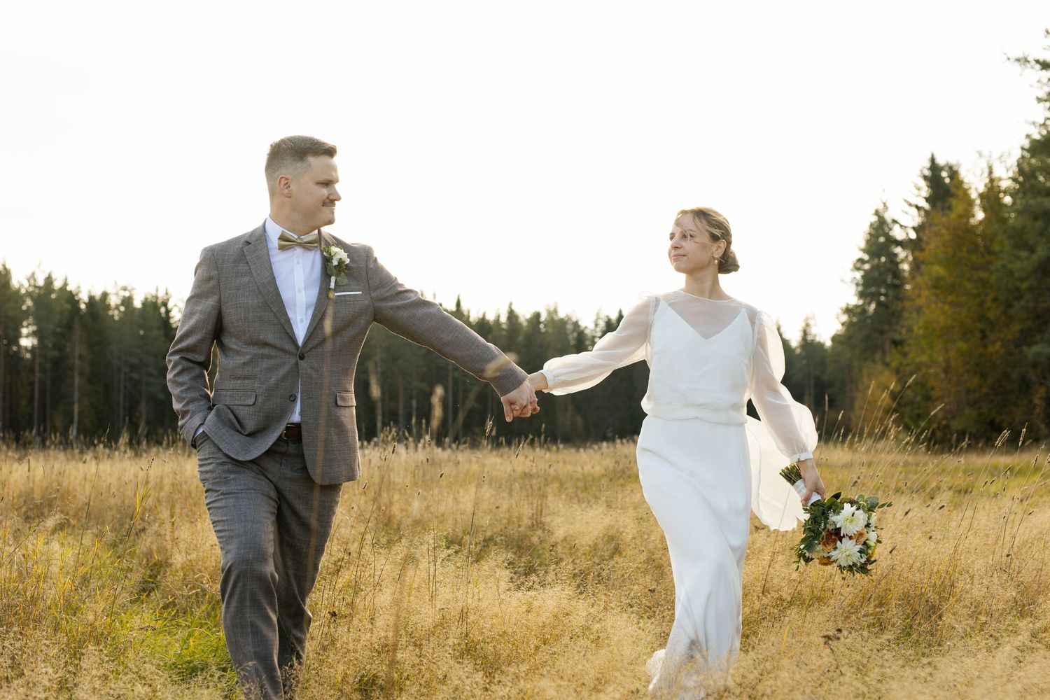 A couple shares a joyful moment together in a golden autumn field at sunset.