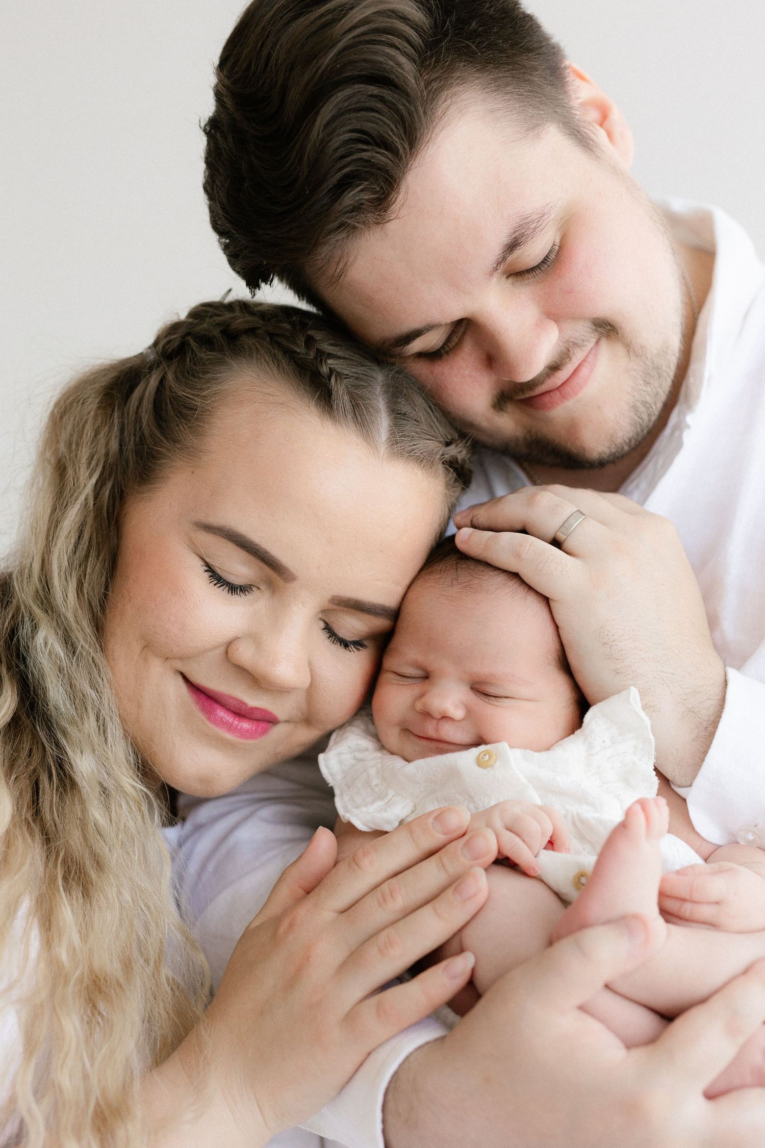 A tender family moment captured in a series of intimate portraits showing parents embracing their newborn baby.