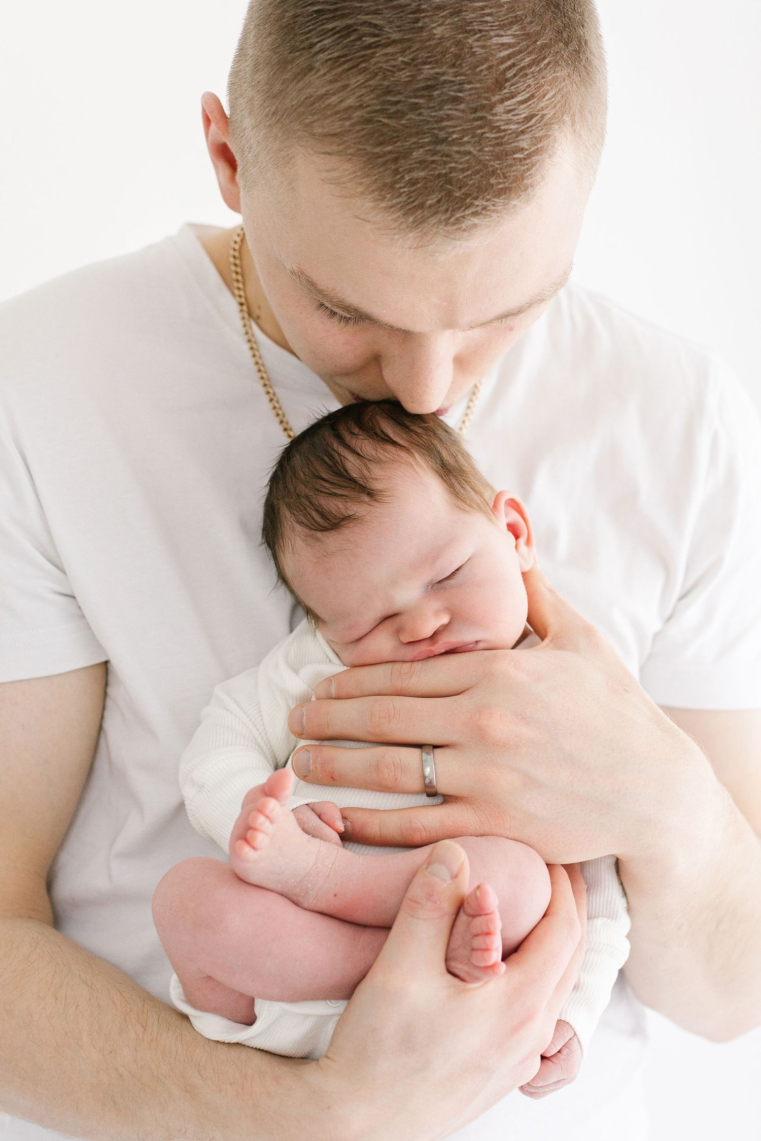 Parent in white shirt tenderly holding sleeping newborn.