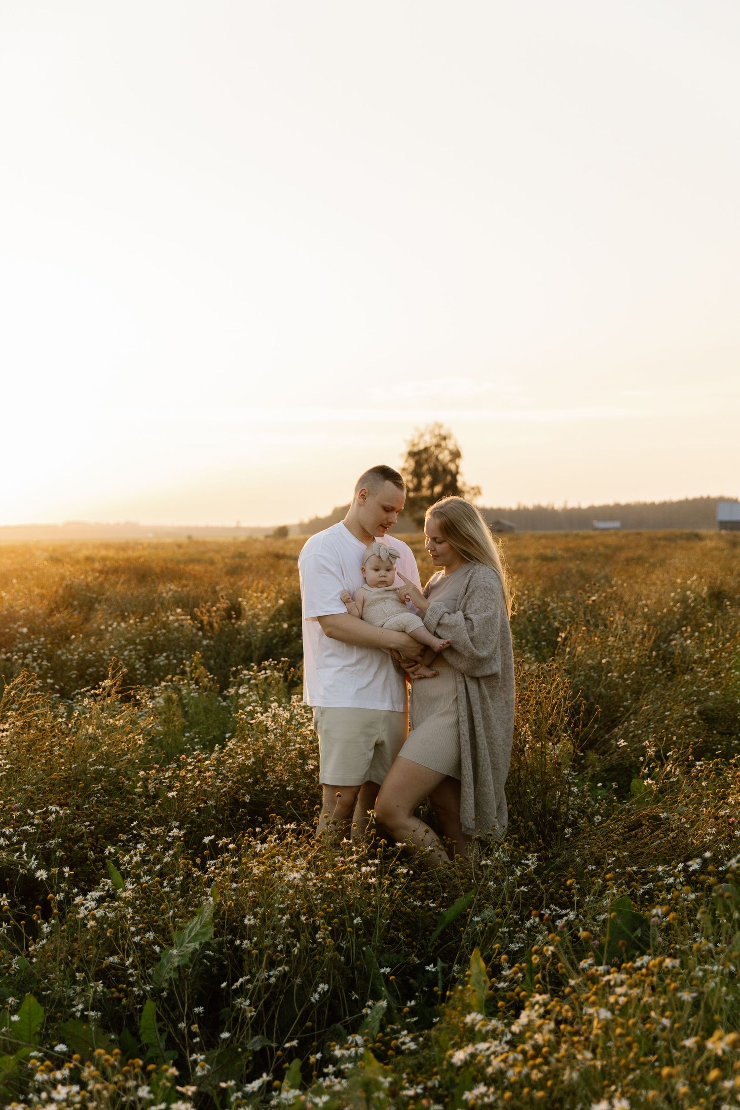Couple embracing in wildflower field during golden hour sunset.