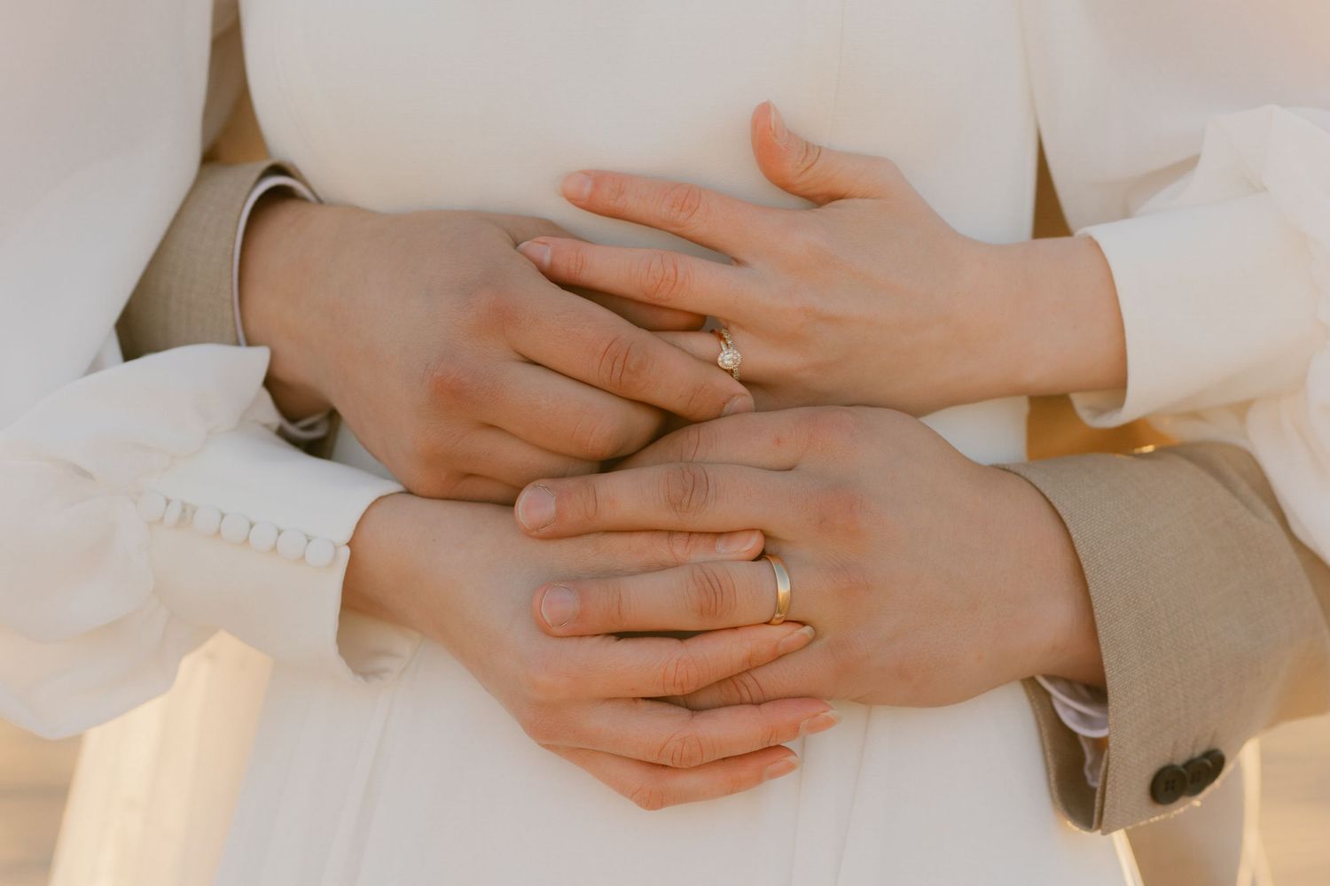 Hands gently rest on a white fabric surface in a series of minimalist, neutral-toned photographs arranged horizontally.