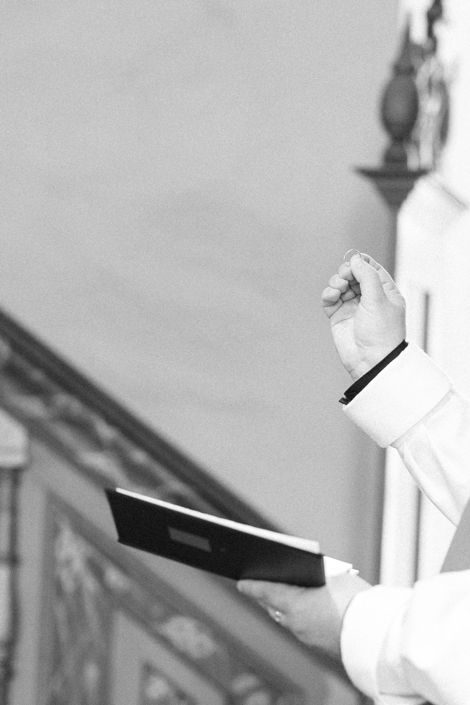Person holding a book during a religious ceremony with hands raised in white robes.