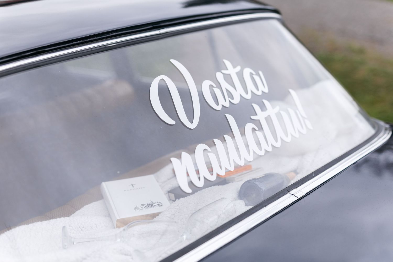 Just Married text in white script lettering on vintage car window.