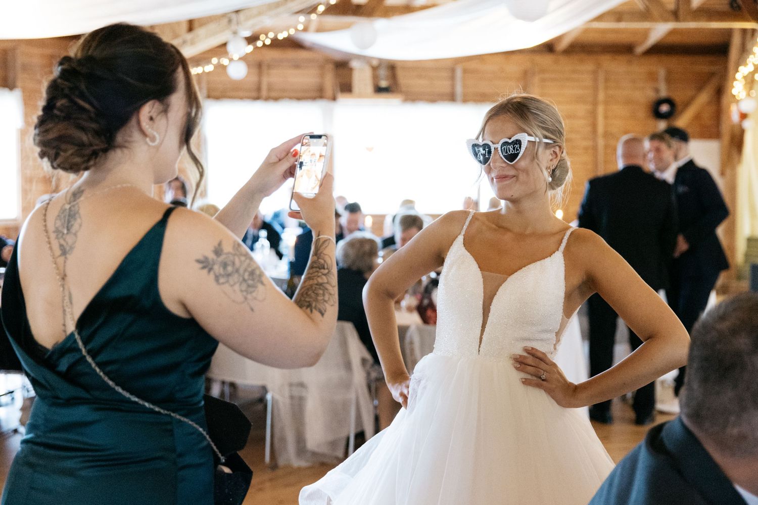 Two people in formal attire share a fun moment on the dance floor at an indoor wedding reception.