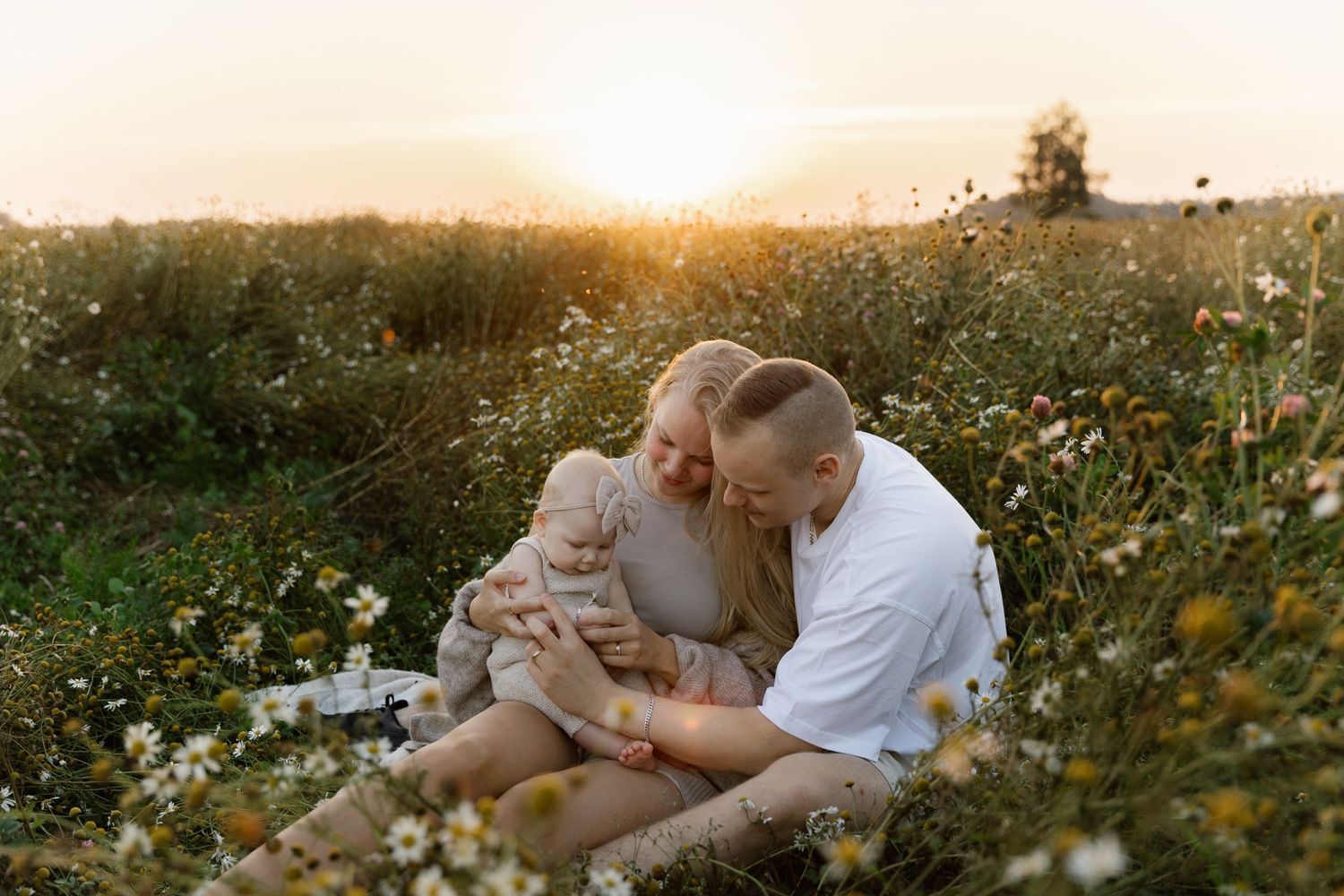 Family enjoying sunset together in wildflower field.
