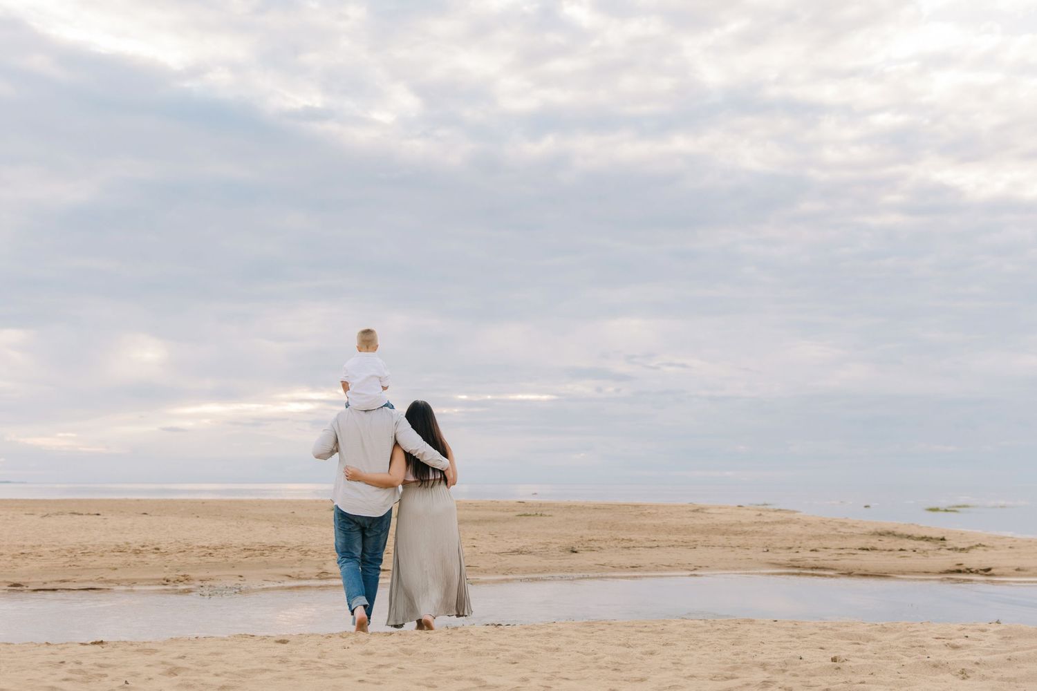 Couple walking hand in hand on a peaceful beach during sunset.