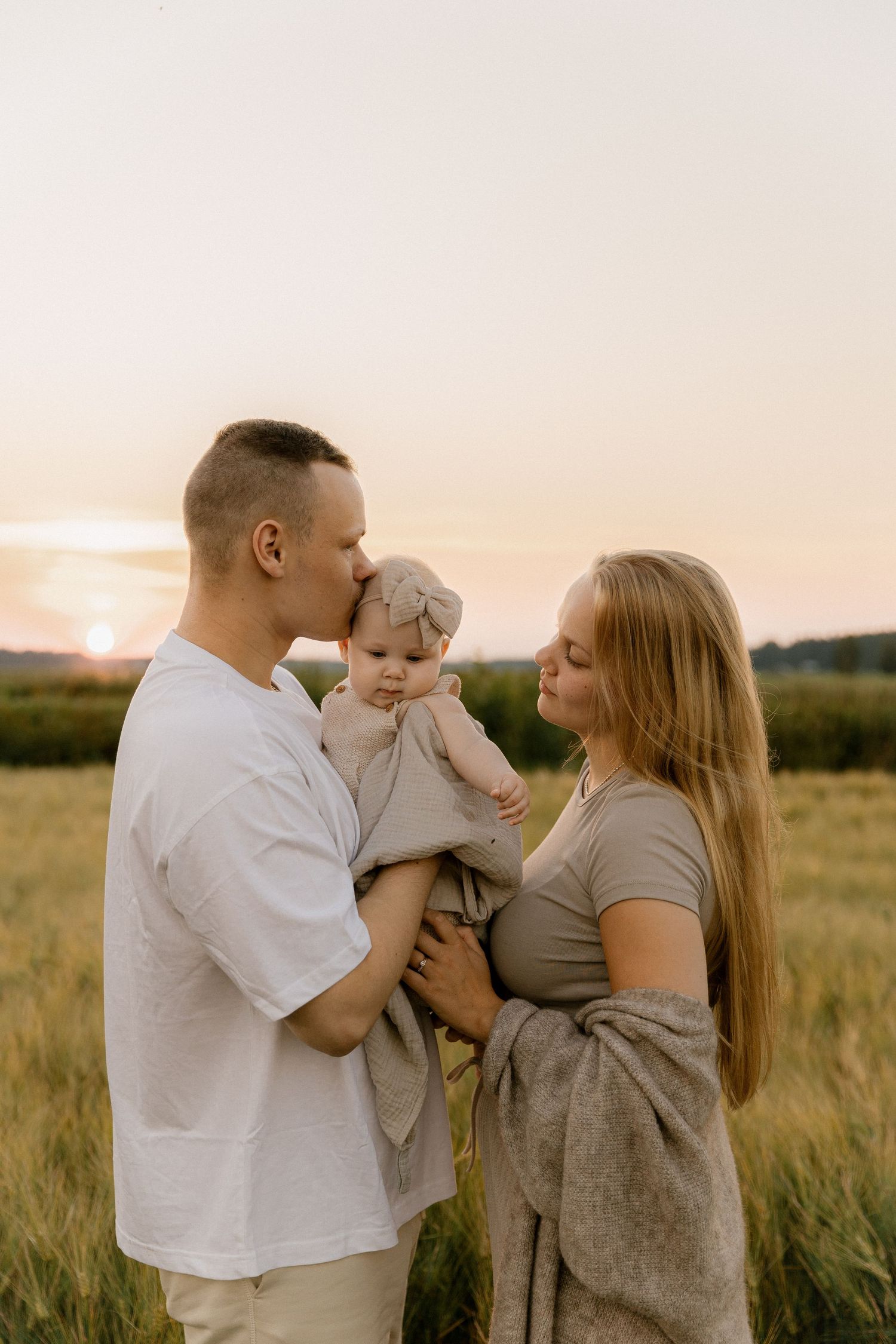 A family shares a tender moment together in a wheat field during golden hour.