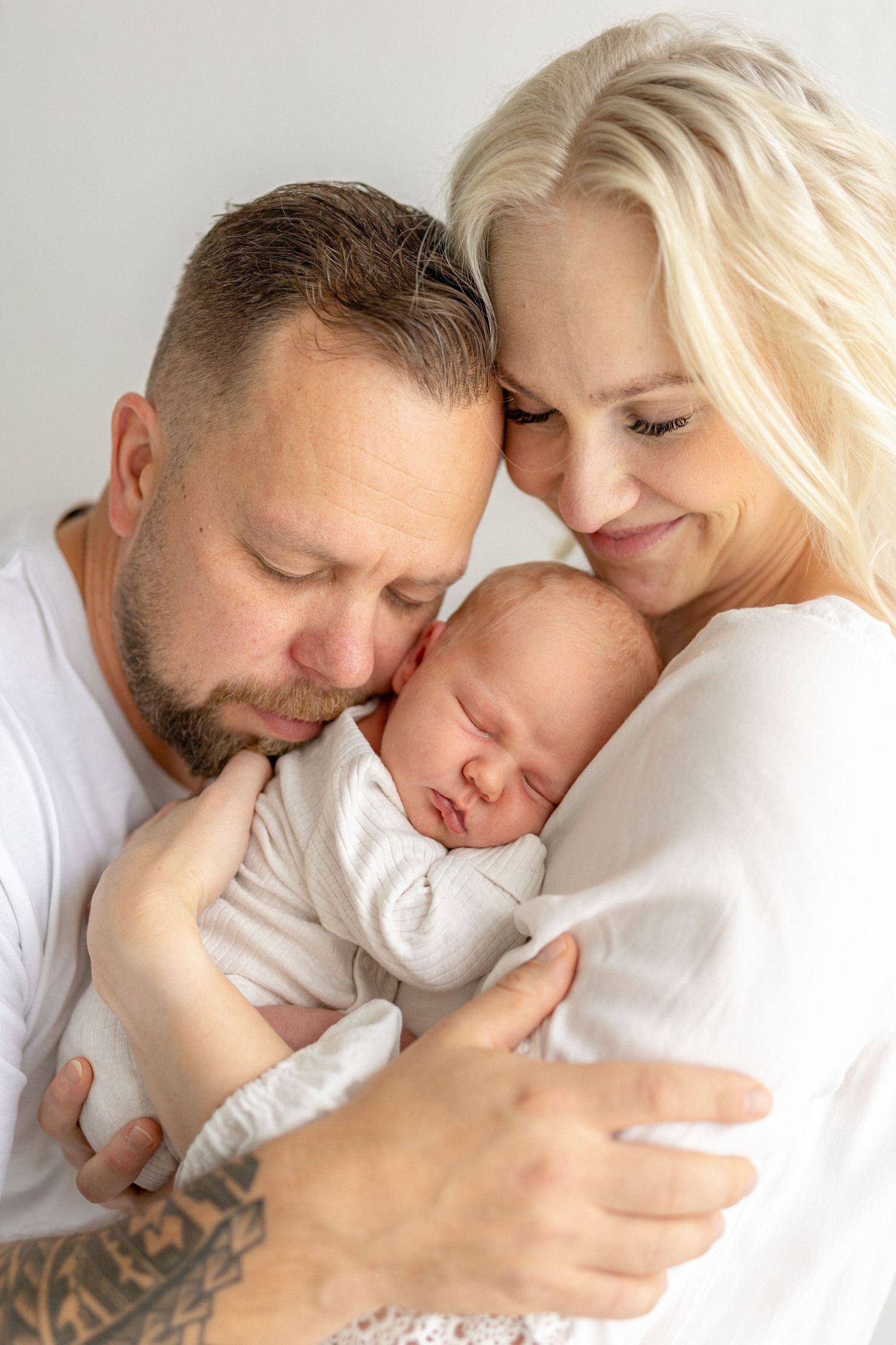 Parents sharing tender moment with sleeping newborn.